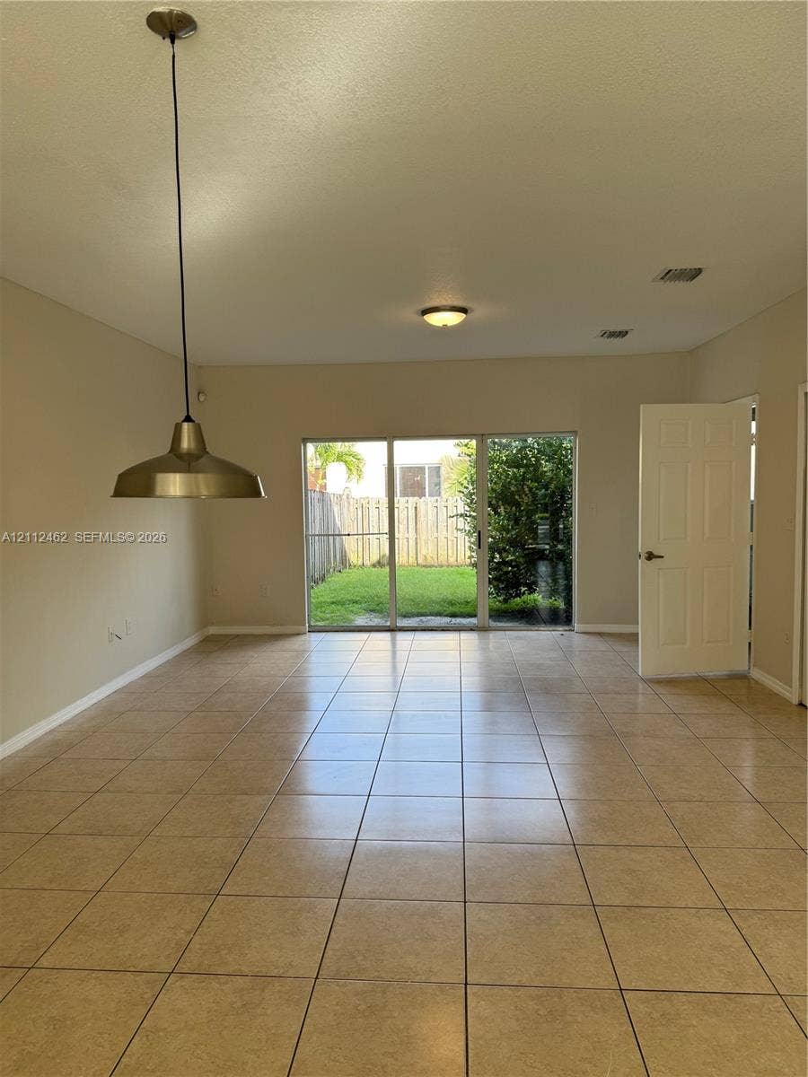 20439 NW 15th Avenue, #9, Miami Gardens, Miami Gardens, FL 33169 Tiled flooring throughout, sliding glass doors, metallic pendant lighting, flush-mount ceiling fixture, and exterior fencing