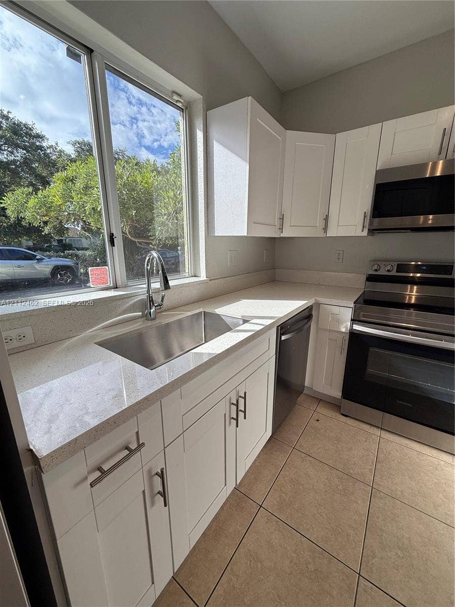 20439 NW 15th Avenue, #9, Miami Gardens, Miami Gardens, FL 33169 Kitchen featuring white shaker-style cabinetry, stainless steel appliances, quartz countertops, an undermount sink with a gooseneck faucet, and tile flooring