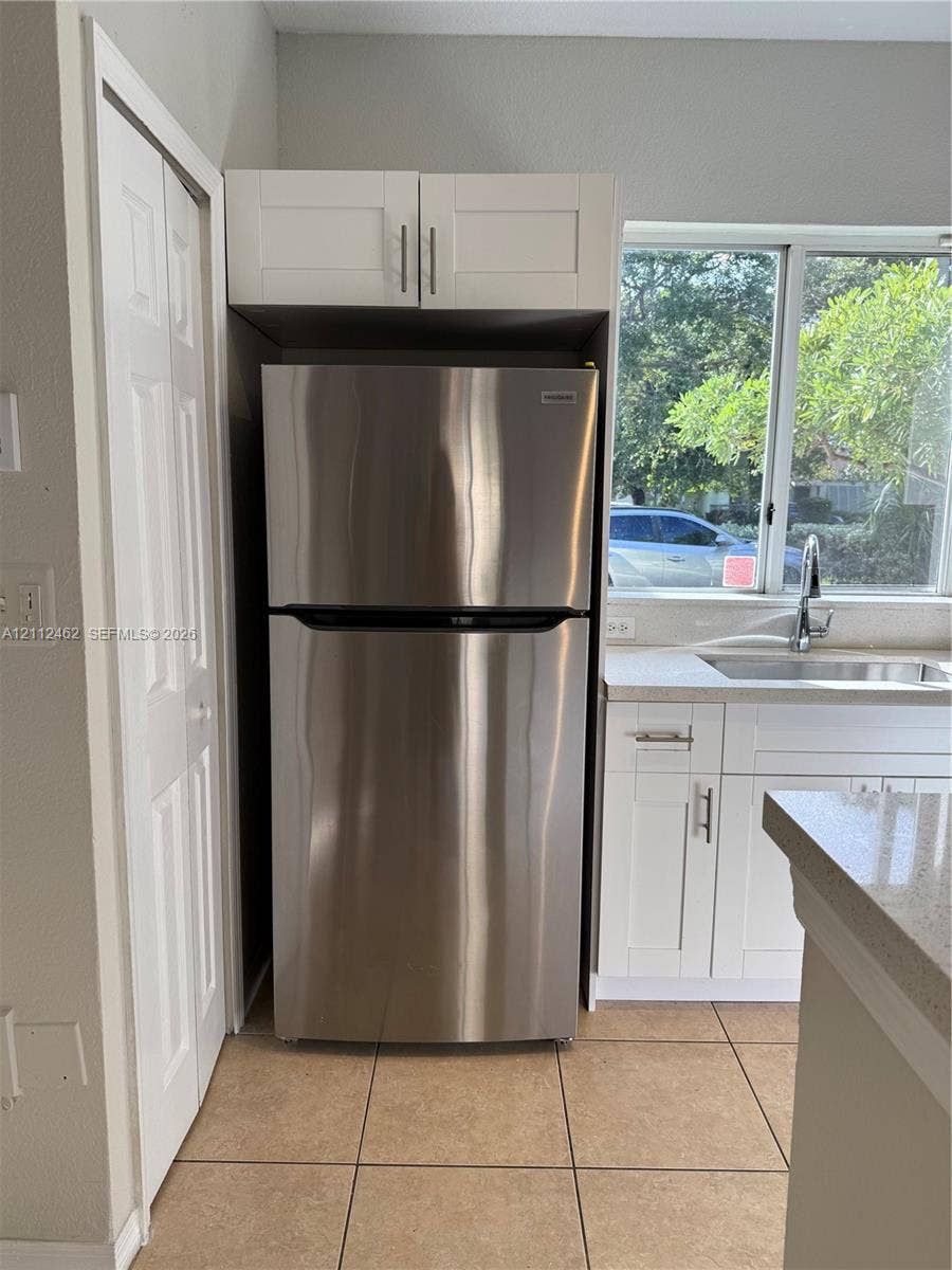 20439 NW 15th Avenue, #9, Miami Gardens, Miami Gardens, FL 33169 Stainless steel refrigerator with overhead built-in cabinetry, shaker-style white lower cabinets, stone-composite countertops, and tiled flooring