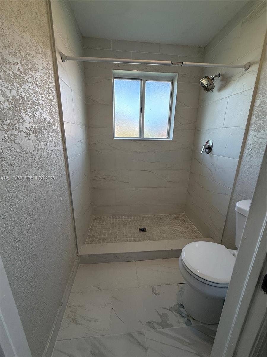 20439 NW 15th Avenue, #9, Miami Gardens, Miami Gardens, FL 33169 Bathroom featuring large-format tile flooring, a walk-in shower with floor-to-ceiling surround tile, a mosaic-tiled shower floor, and a single-handle wall-mounted shower fixture
