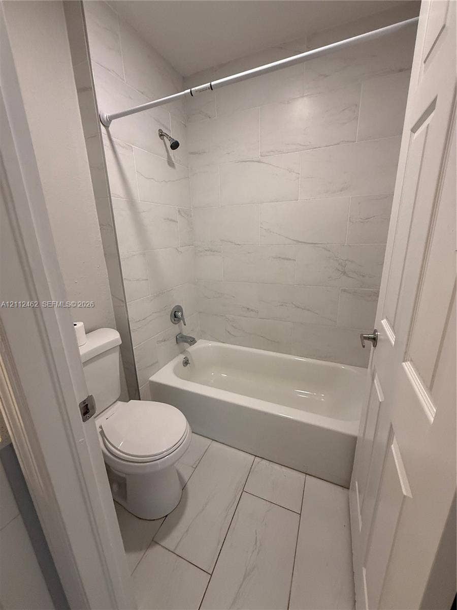 20439 NW 15th Avenue, #9, Miami Gardens, Miami Gardens, FL 33169 Full bathroom featuring large-format light-toned tile flooring, a tub-shower combination, and wall-to-wall light-toned tile surround