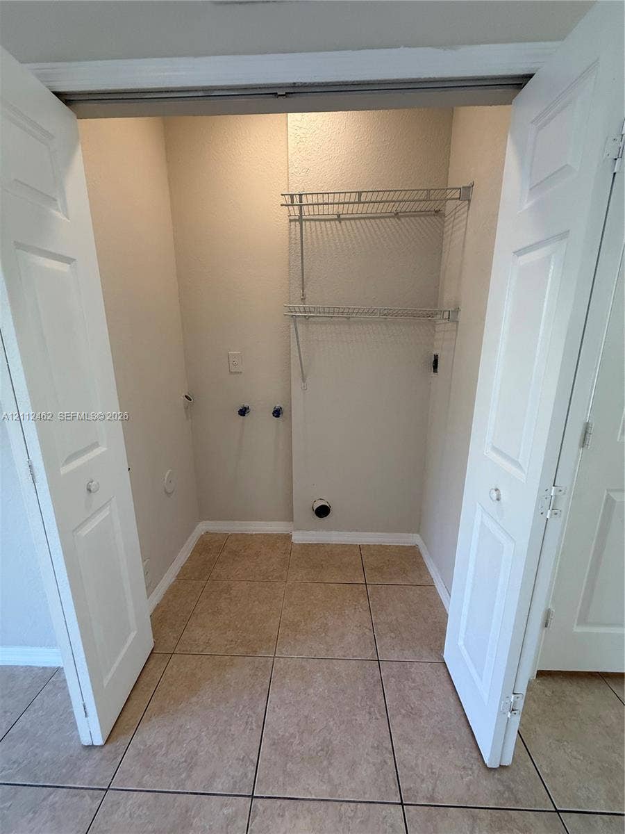 20439 NW 15th Avenue, #9, Miami Gardens, Miami Gardens, FL 33169 Utility closet featuring tile flooring, bi-fold doors, and integrated wire shelving