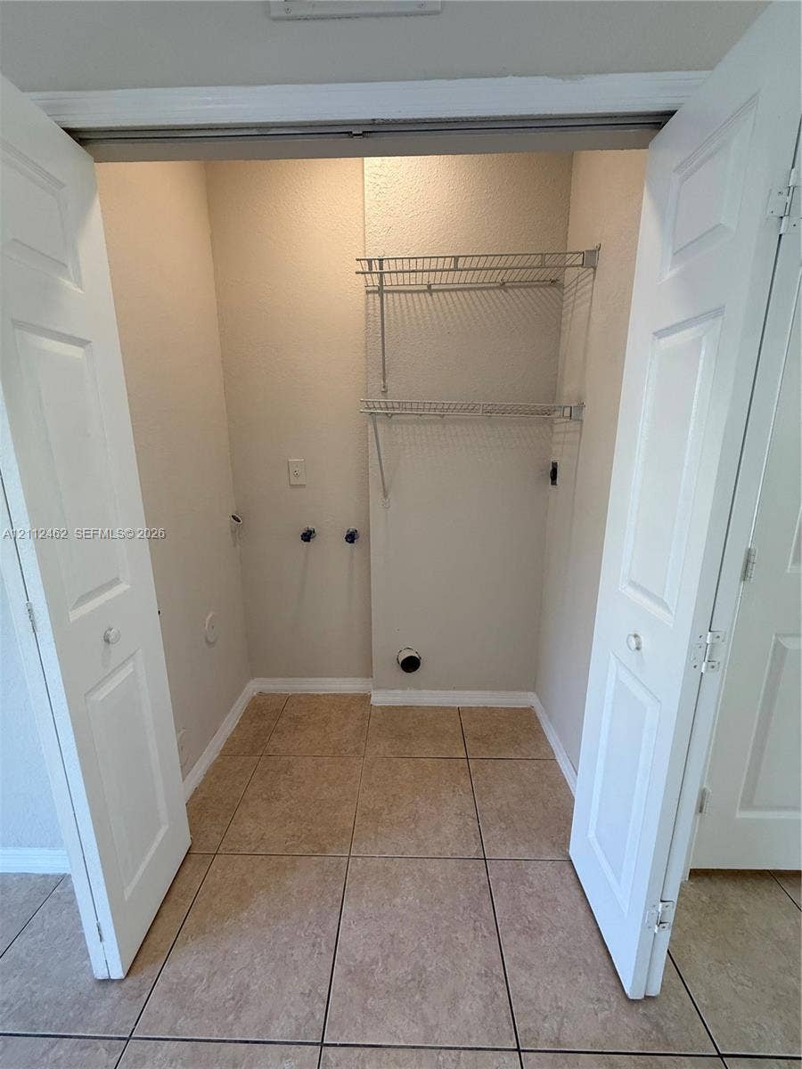 20439 NW 15th Avenue, #9, Miami Gardens, Miami Gardens, FL 33169 Utility closet featuring dual-folding doors, tile flooring, and integrated metal shelving