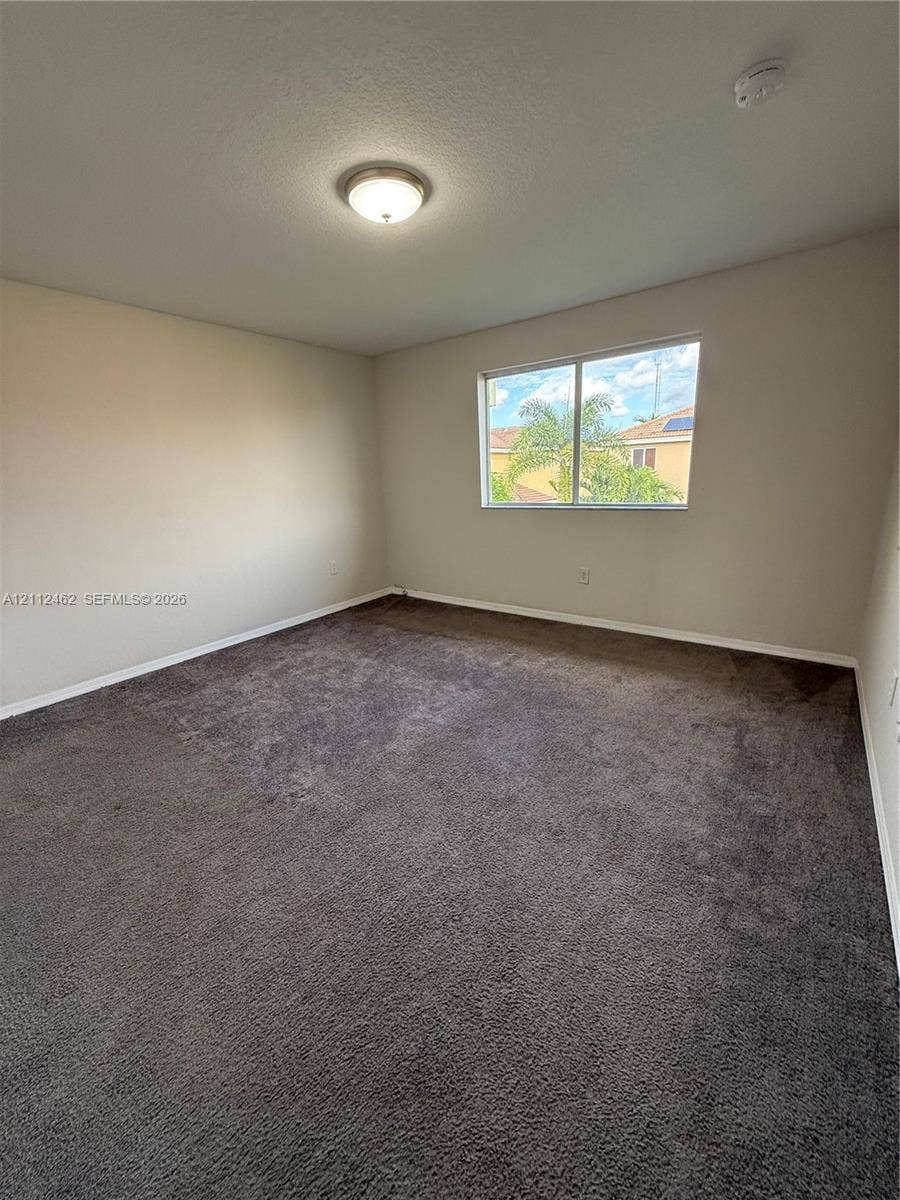 20439 NW 15th Avenue, #9, Miami Gardens, Miami Gardens, FL 33169 Neutral-toned interior space featuring wall-to-wall carpeting, a flush-mount ceiling light fixture, and a single-pane window
