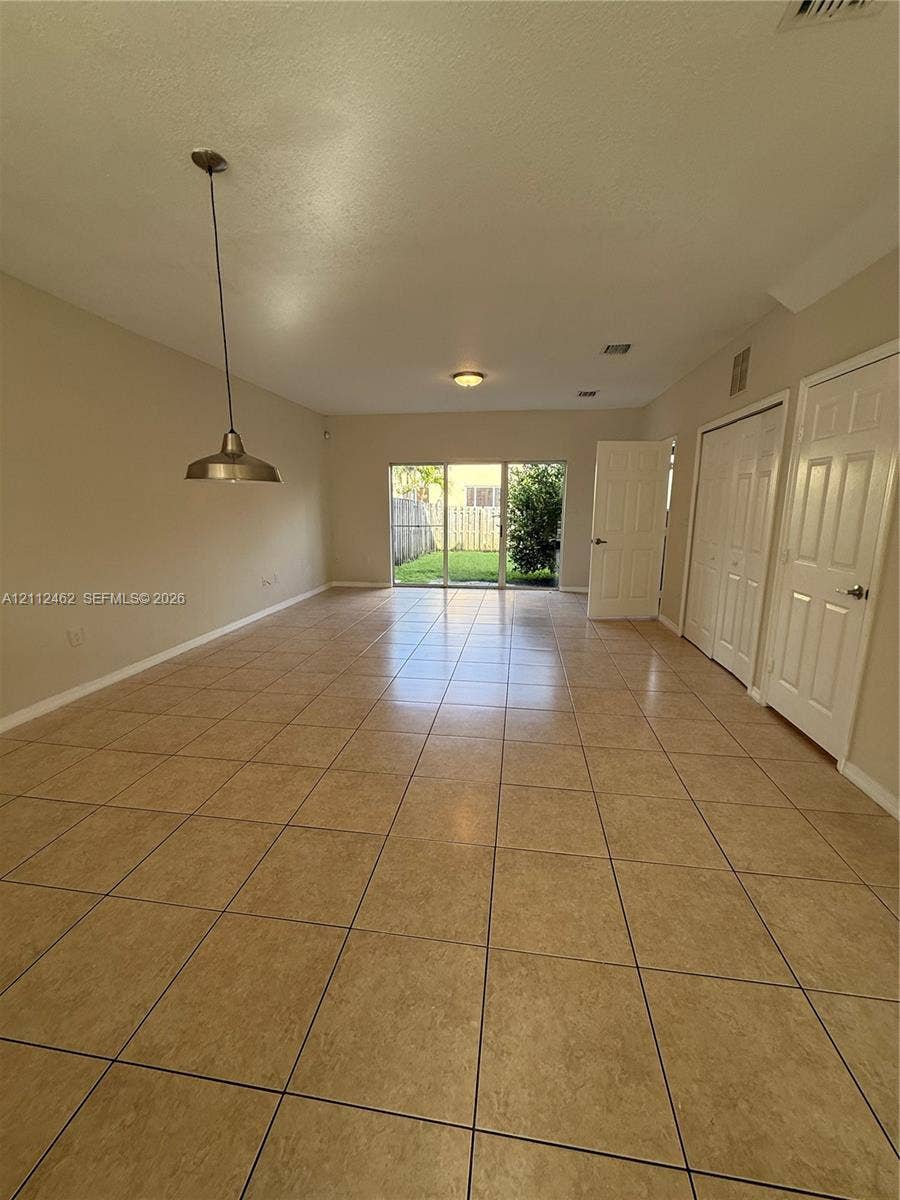 20439 NW 15th Avenue, #9, Miami Gardens, Miami Gardens, FL 33169 Interior space featuring neutral wall paint, large format ceramic tile flooring, a metal pendant light fixture, sliding glass doors, and interior paneled doors