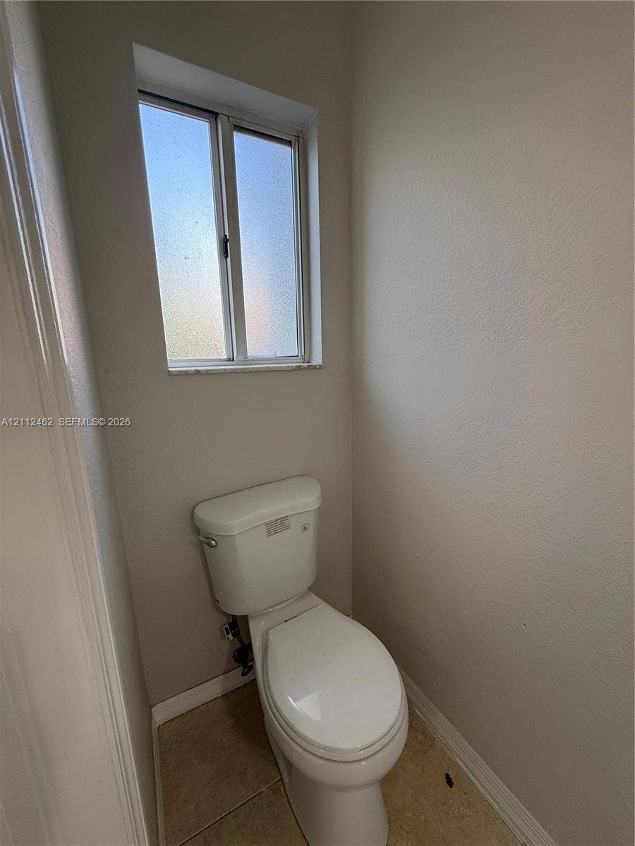 20439 NW 15th Avenue, #9, Miami Gardens, Miami Gardens, FL 33169 Ceramic tile flooring, white porcelain toilet, and a privacy-glass window with a stone sill