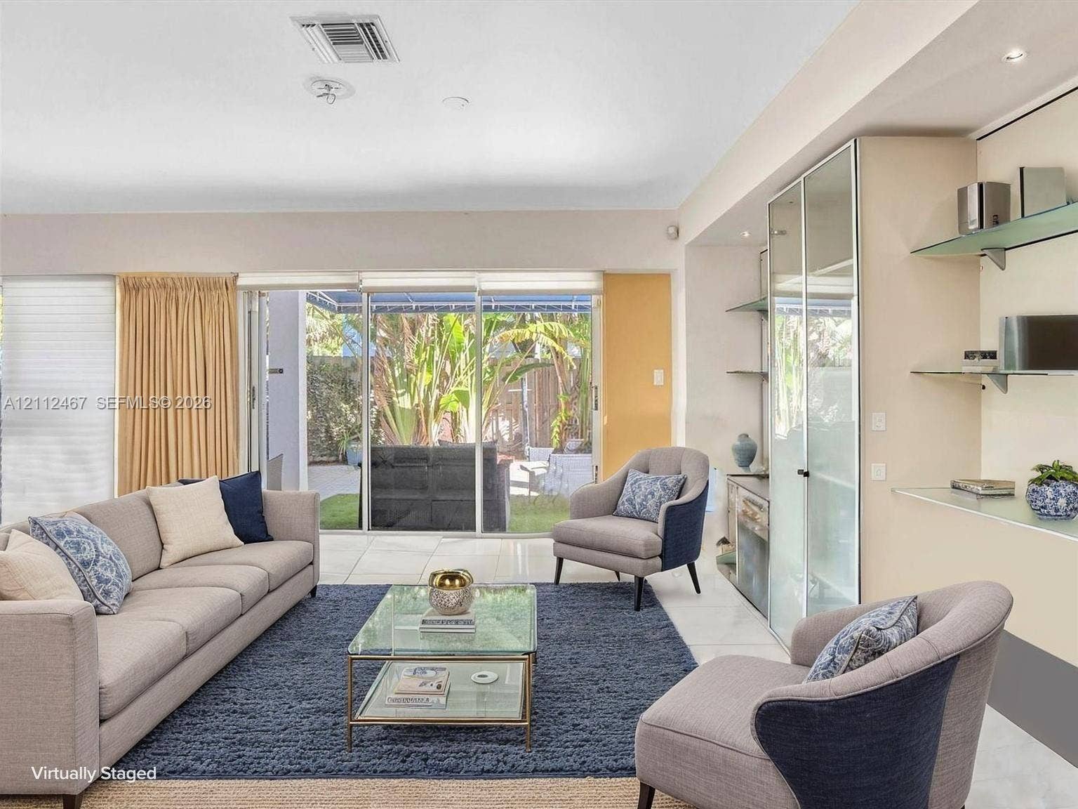 250 NE 212th Street, Miami, Miami, FL 33179 Living space featuring large sliding glass doors, built-in display cabinetry with glass shelving, and light-tone tile flooring
