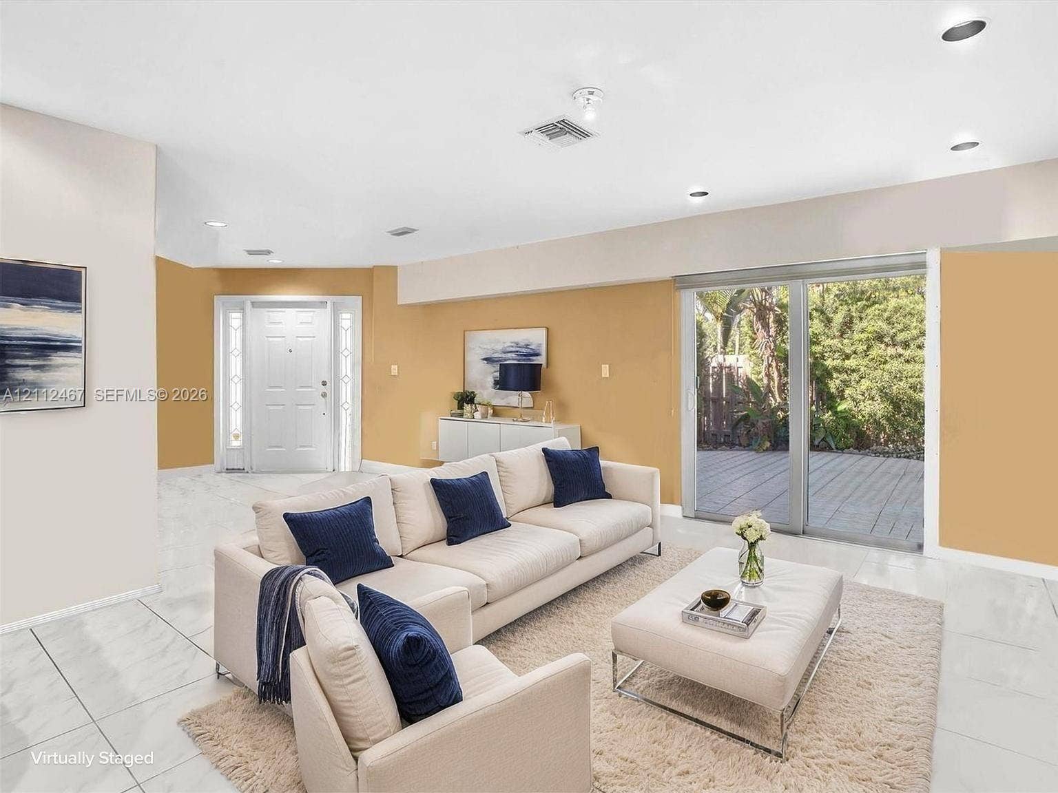 250 NE 212th Street, Miami, Miami, FL 33179 Open-concept interior featuring light-toned tile flooring, recessed ceiling lighting, a multi-panel front door with sidelights, and large glass sliding doors providing exterior deck access