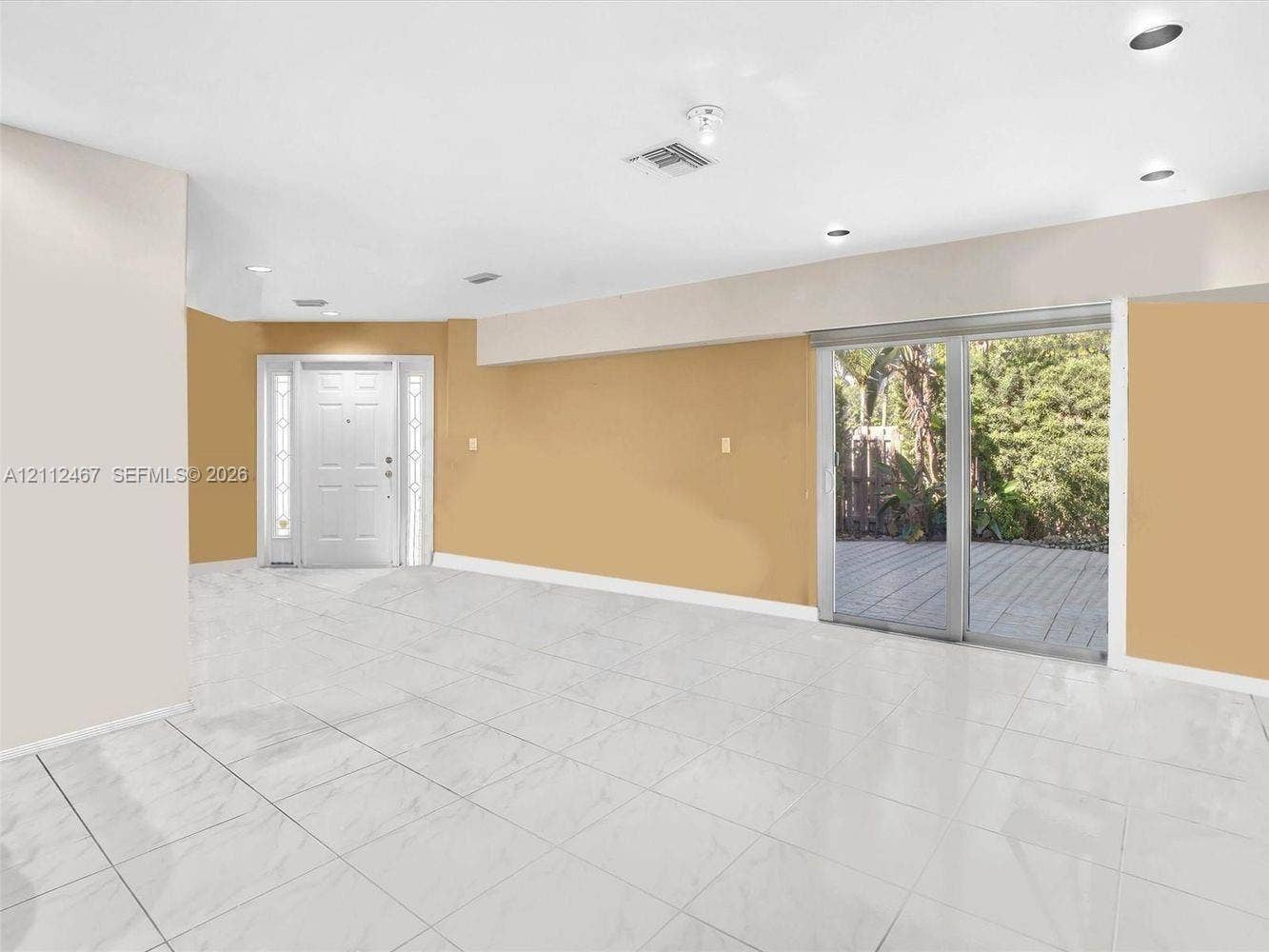 250 NE 212th Street, Miami, Miami, FL 33179 Neutral-toned interior featuring large-format tile flooring, recessed ceiling lighting, a multi-panel glass sliding door, and a paneled entry door with sidelights