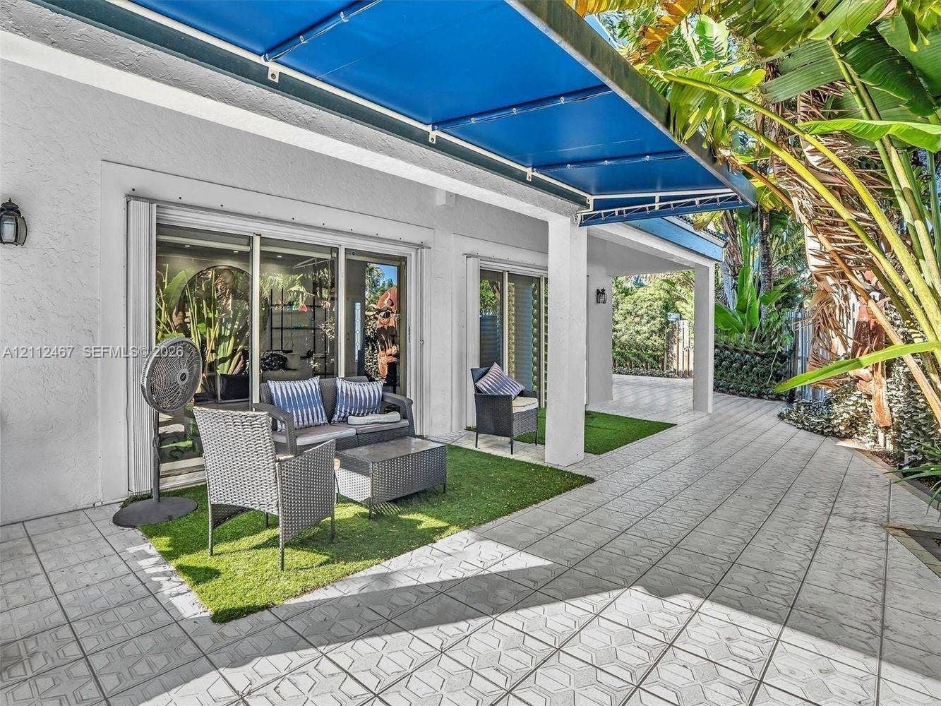 250 NE 212th Street, Miami, Miami, FL 33179 Covered patio featuring patterned tile flooring, retractable blue fabric awning, and recessed sliding glass doors
