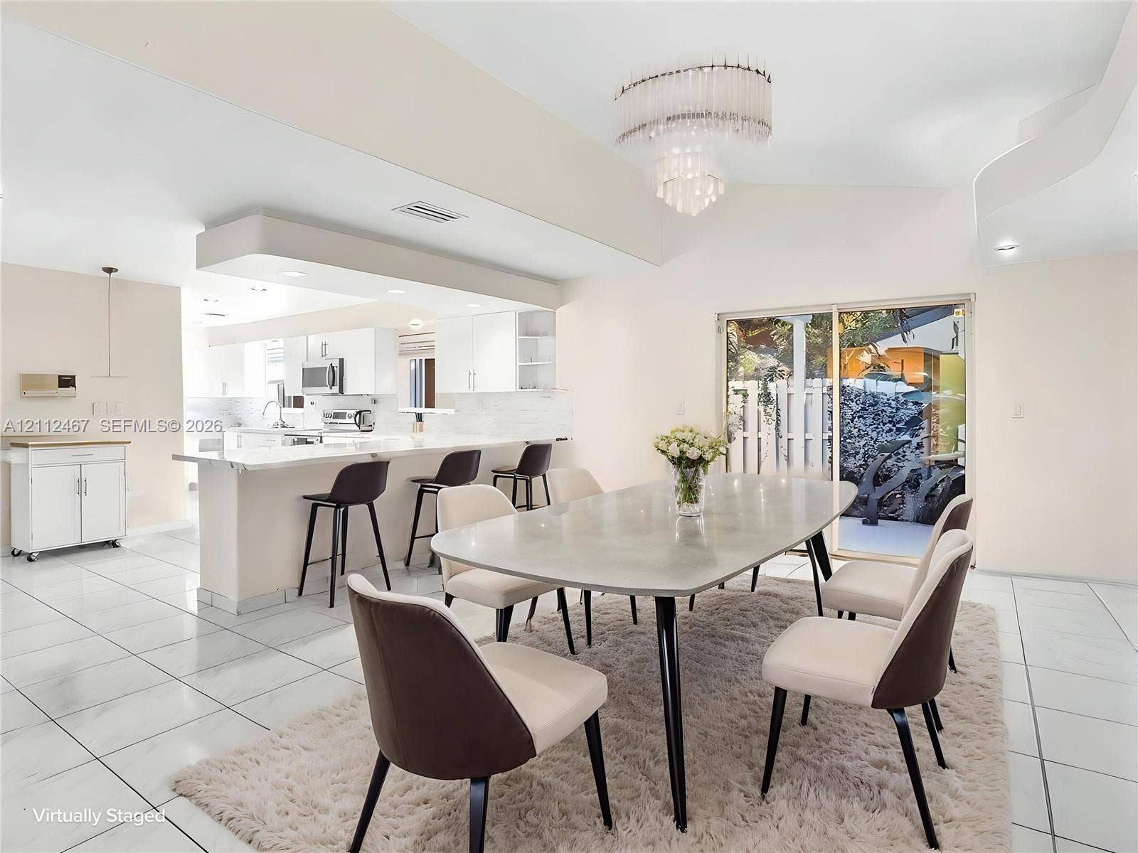 250 NE 212th Street, Miami, Miami, FL 33179 Open-concept kitchen featuring white cabinetry, a spacious breakfast bar, multi-tiered tiered chandelier lighting, and large-format tile flooring