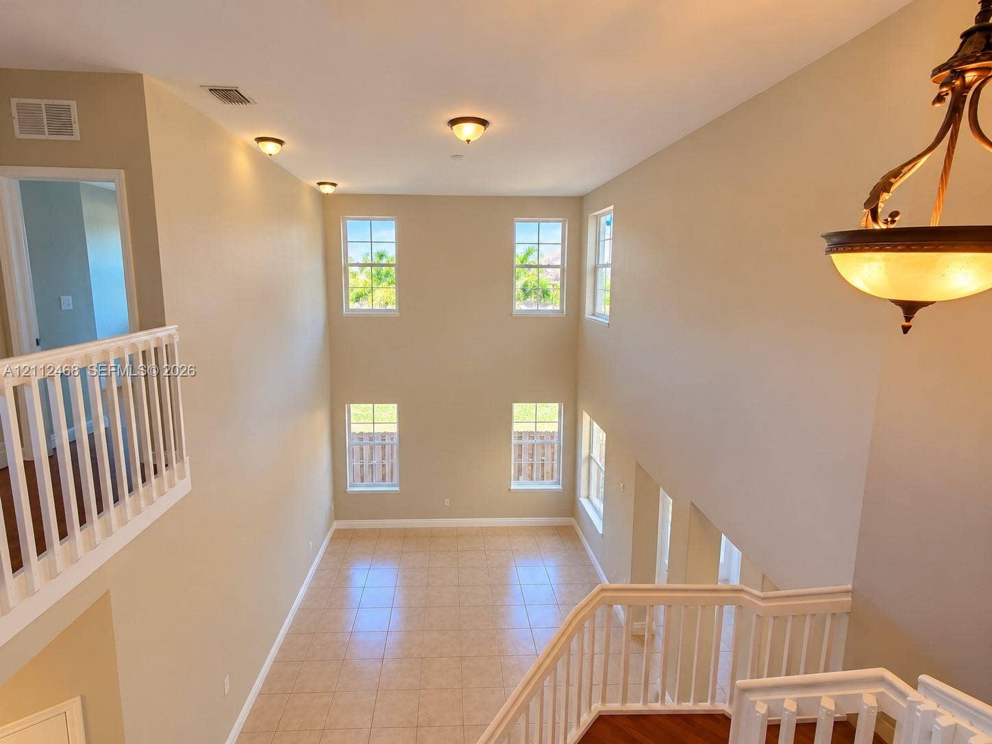 11009 NW 80th Lane, Doral, FL 33178 Double-height ceiling, large windows with natural light, tile flooring, and white spindle railings