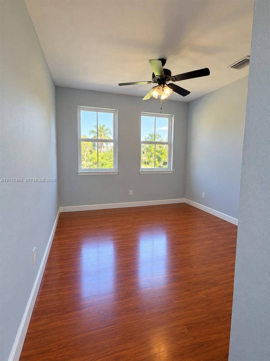 11009 NW 80th Lane, Doral, FL 33178 Room featuring wood-finish flooring, dual windows with grid detailing, and a multi-light ceiling fan