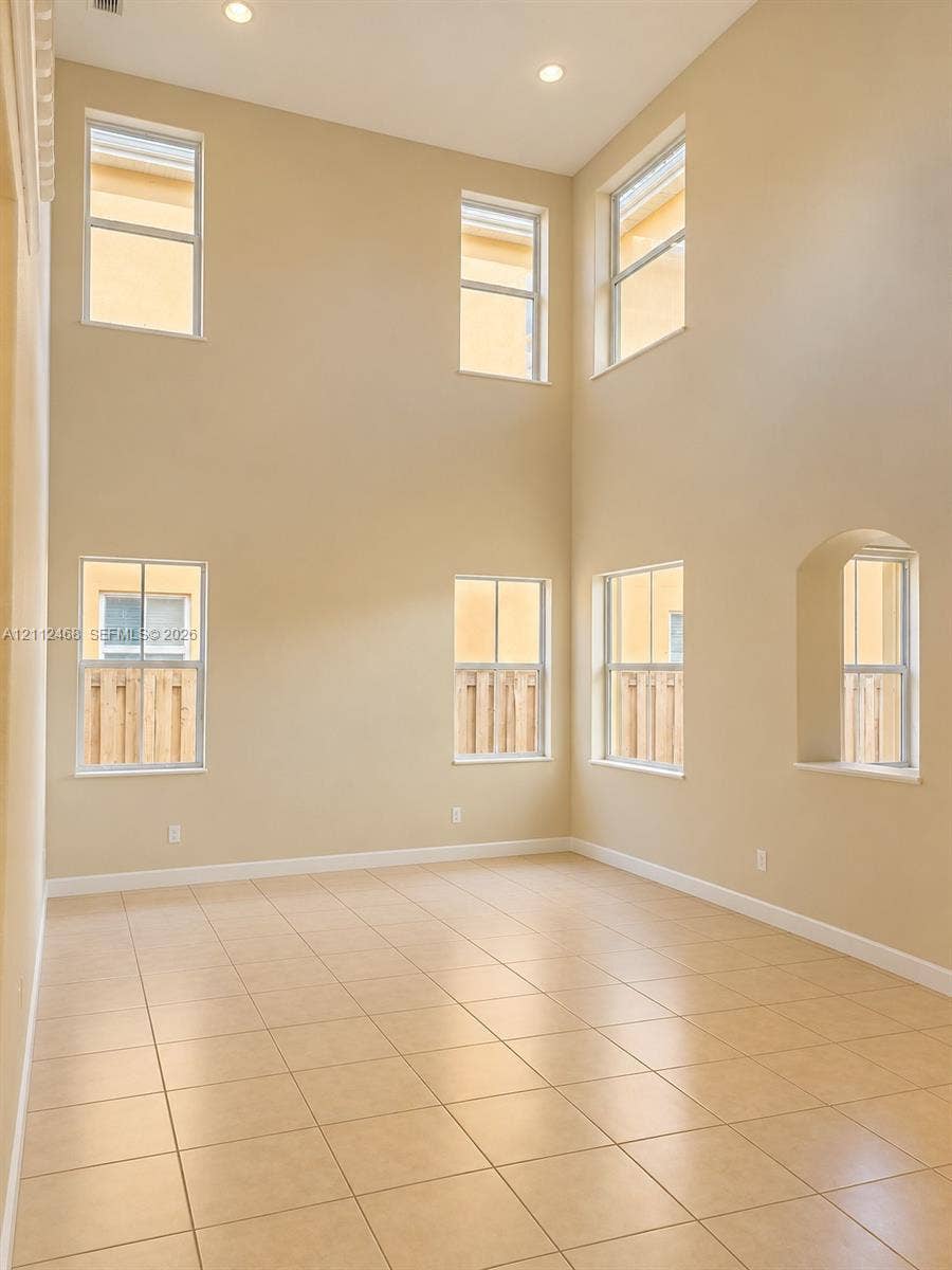 11009 NW 80th Lane, Doral, FL 33178 Double-height ceilings featuring recessed lighting, large-format tile flooring, and multiple window placements including a signature arched window