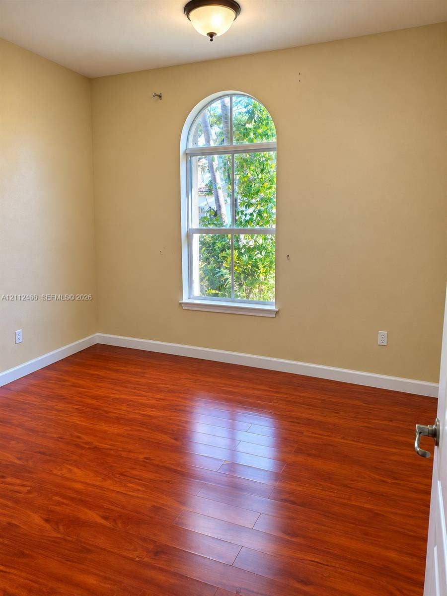 11009 NW 80th Lane, Doral, FL 33178 Room featuring arched window, wood-finish flooring, and overhead flush-mount lighting