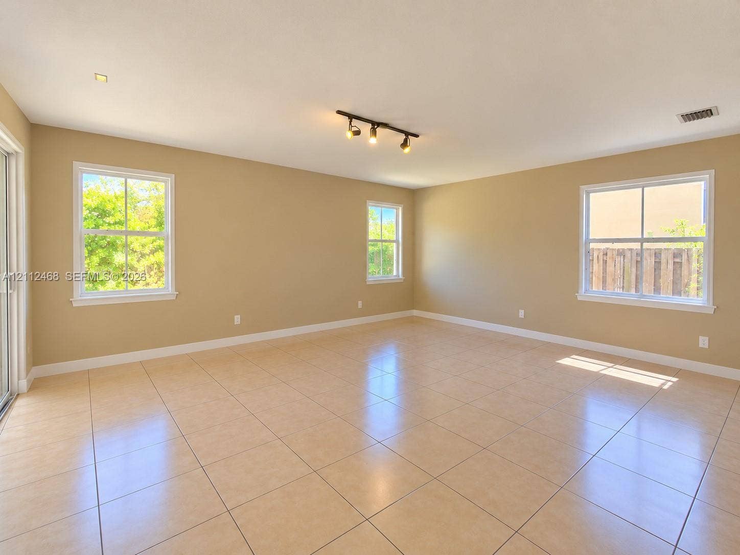 11009 NW 80th Lane, Doral, FL 33178 Neutral-toned interior featuring ceramic tile flooring, three multi-pane windows, and a ceiling-mounted track lighting fixture