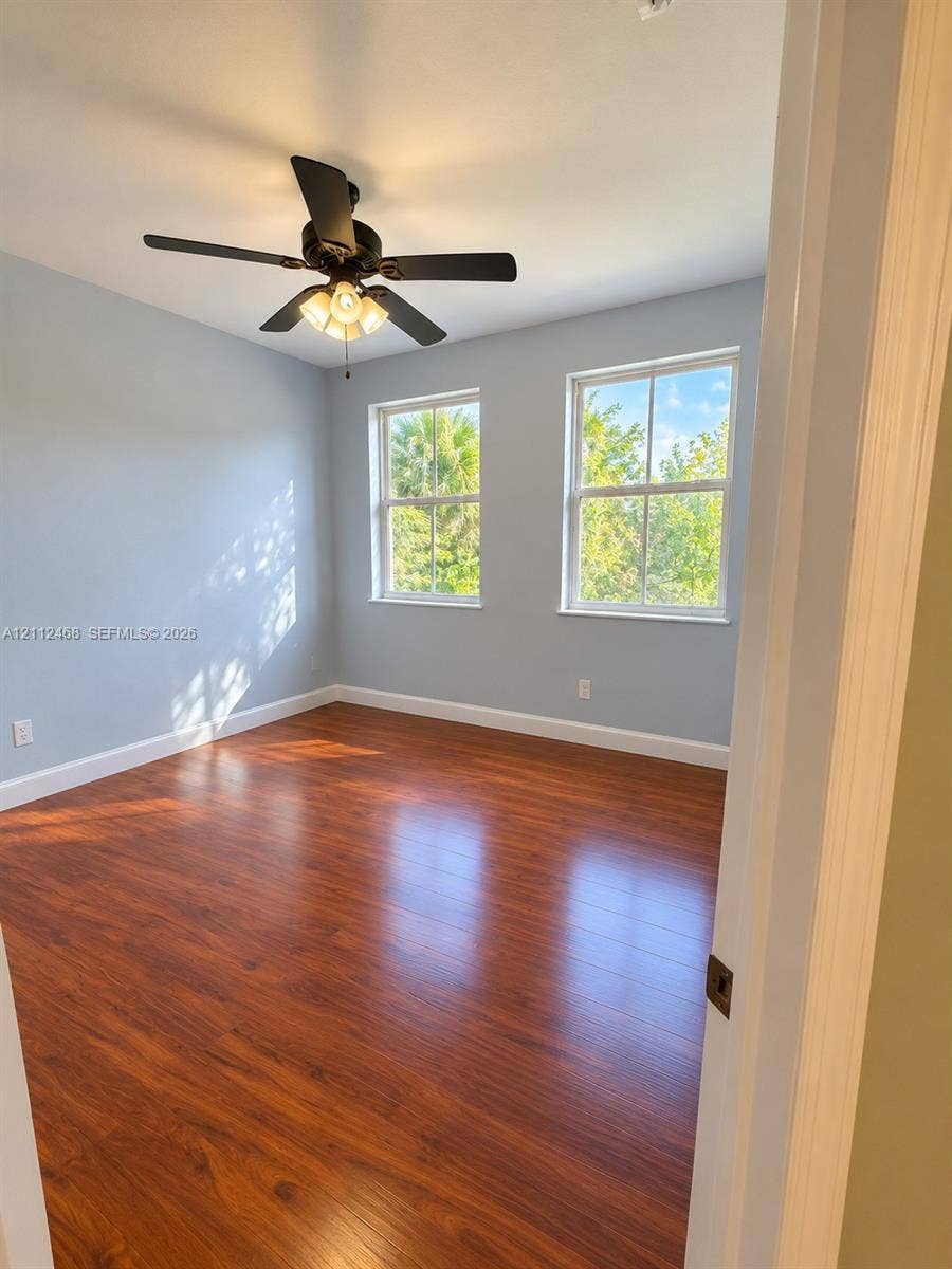 11009 NW 80th Lane, Doral, FL 33178 Room featuring wood-finish flooring, dual windows with muntins, and a ceiling fan with integrated lighting