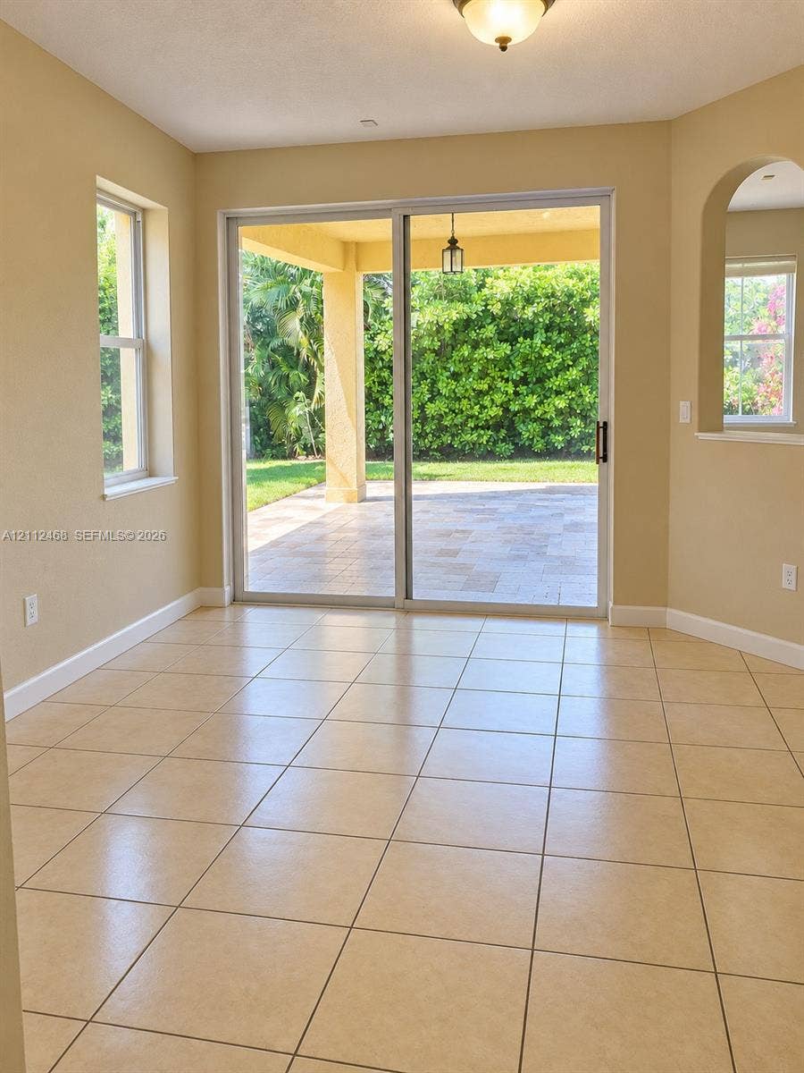 11009 NW 80th Lane, Doral, FL 33178 Tile flooring, sliding glass door, arched wall opening, and covered exterior patio with stone-finish pavers