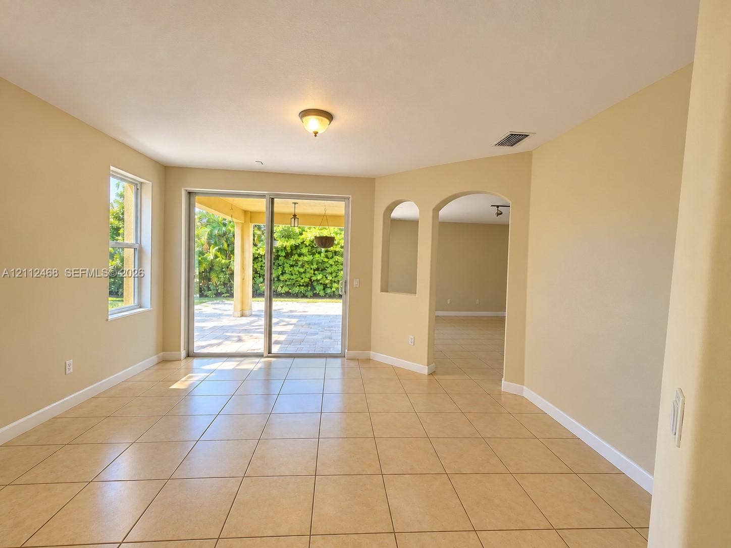 11009 NW 80th Lane, Doral, FL 33178 Ceramic tile flooring, arched wall openings, and sliding glass doors opening to a covered patio