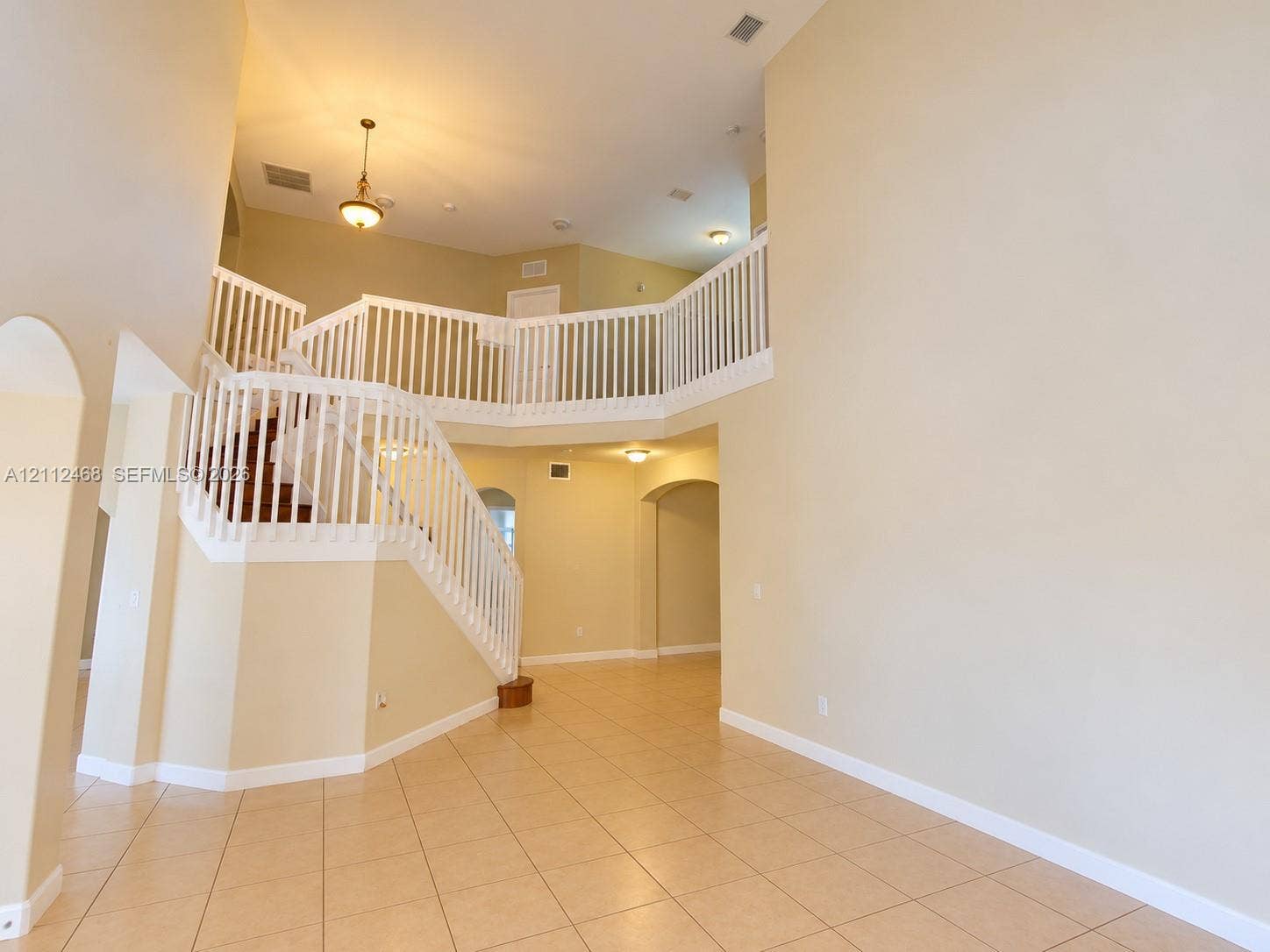 11009 NW 80th Lane, Doral, FL 33178 Two-story foyer featuring high ceilings, tile flooring, an open staircase with white balusters, arched entryways, and pendant lighting