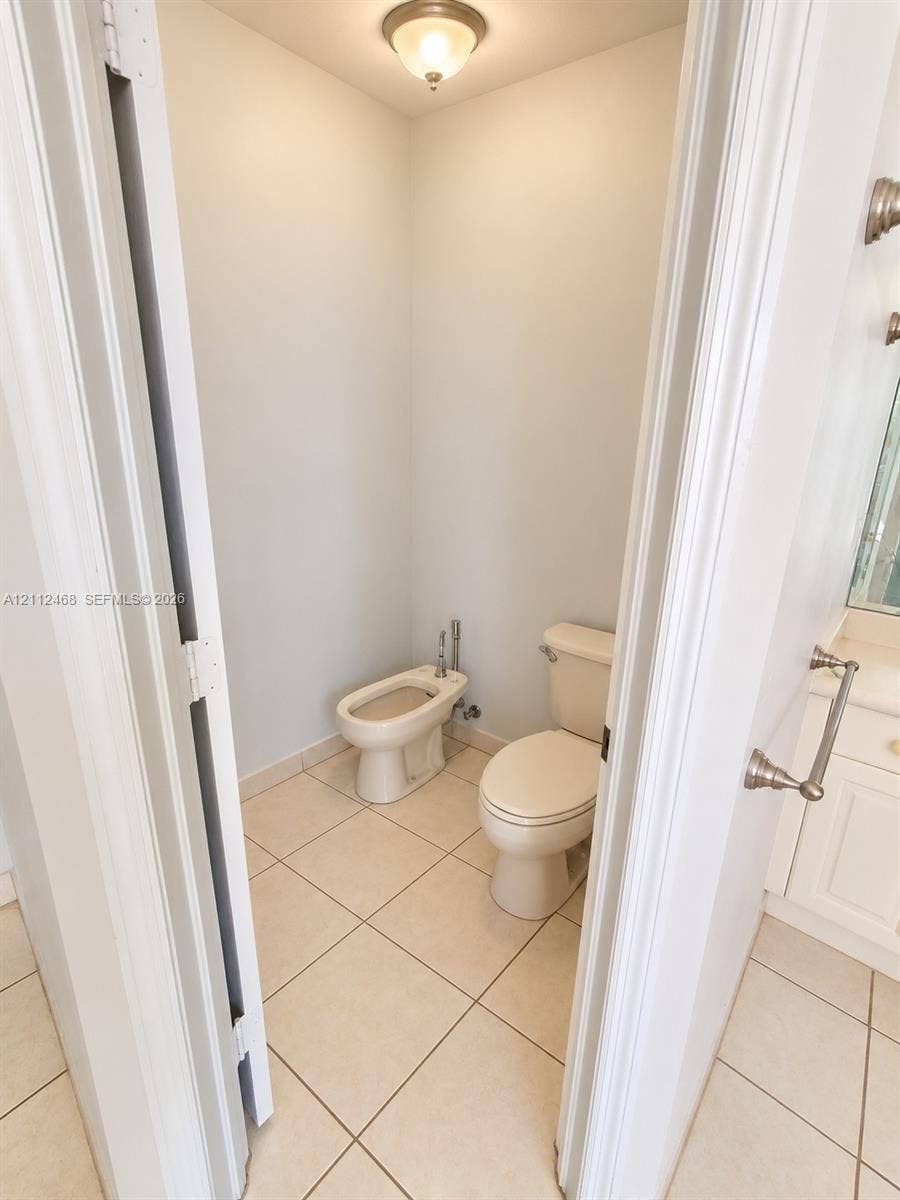 11009 NW 80th Lane, Doral, FL 33178 Water closet featuring a two-piece toilet, bidet, neutral tile flooring, and a flush-mount ceiling light fixture