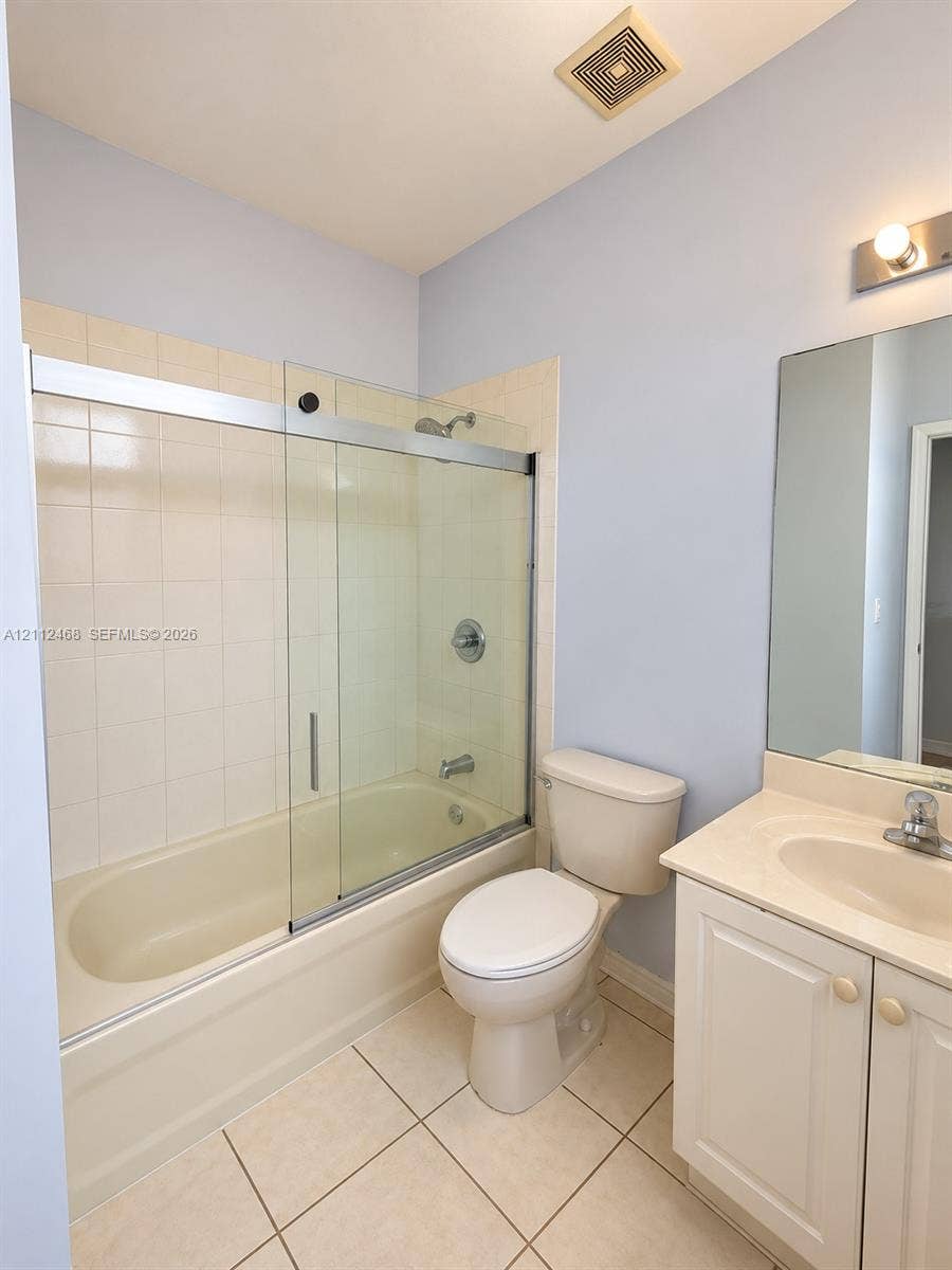 11009 NW 80th Lane, Doral, FL 33178 Bathroom featuring a tub-shower combination with glass sliding doors, ceramic tile shower surround, vanity with an integrated sink, and large wall-mounted mirror