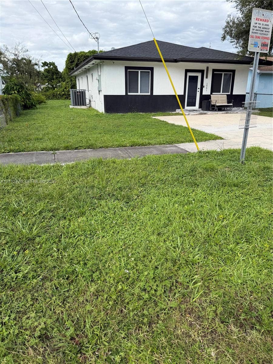Single-story residence featuring high-contrast exterior finishes, a concrete driveway, and an expansive grass lawn
