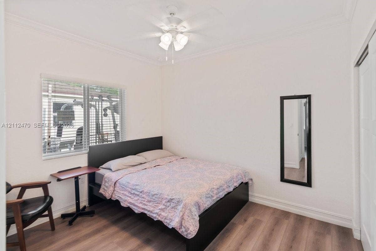 Room featuring wood-finish flooring, neutral wall paint, a multi-light ceiling fan, and horizontal window blinds