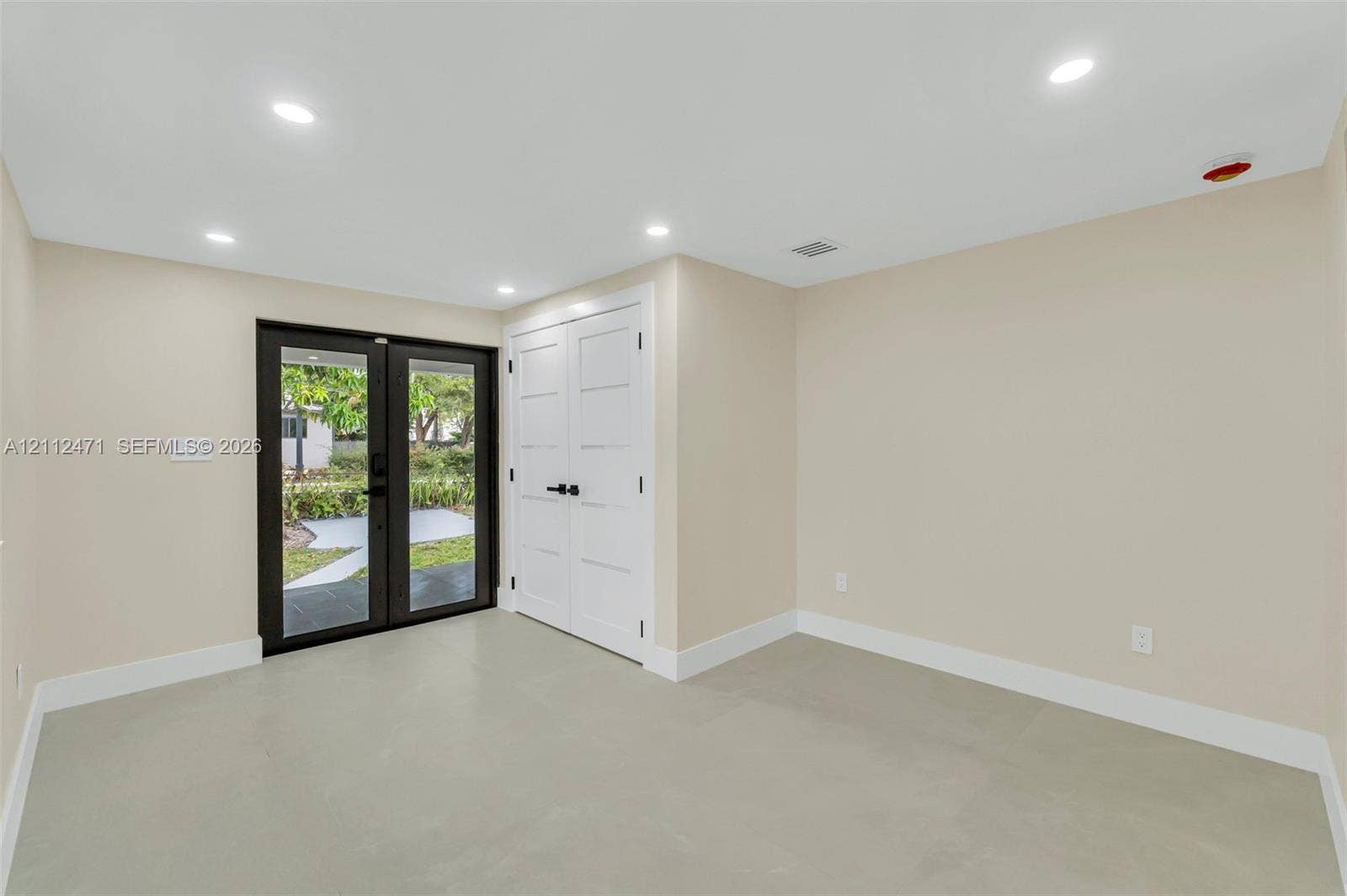 Interior space featuring recessed lighting, smooth-finish flooring, double-door closet with matte black hardware, and glass-paned double doors with dark framing
