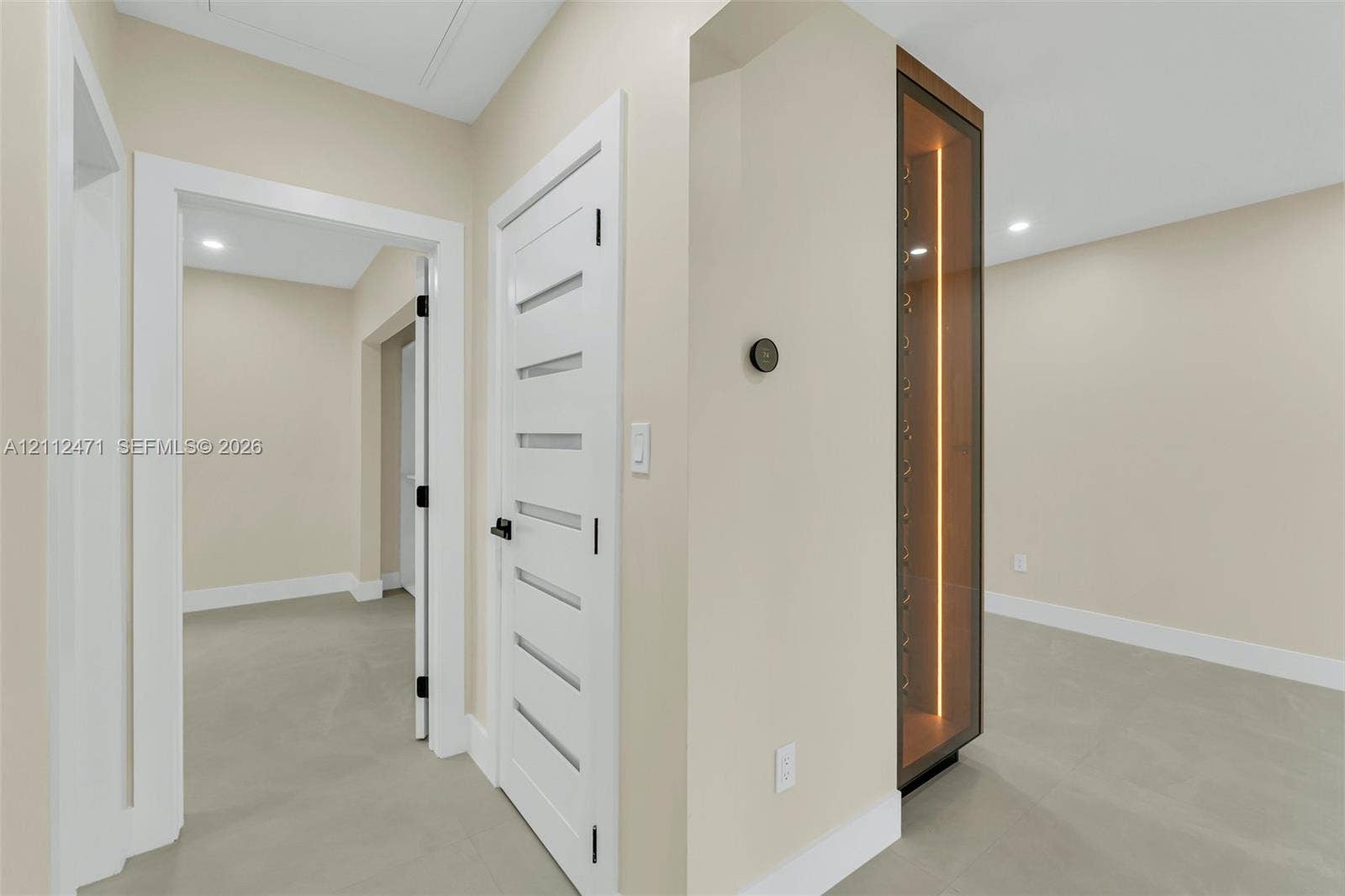 Built-in glass-paneled display cabinet with integrated vertical lighting, solid-core interior doors with horizontal glass inserts, matte black hardware, and neutral-tone flooring