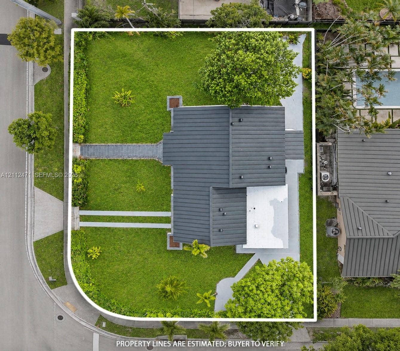 Corner lot featuring extensive lawn space, mature perimeter landscaping, and dual paved walkways