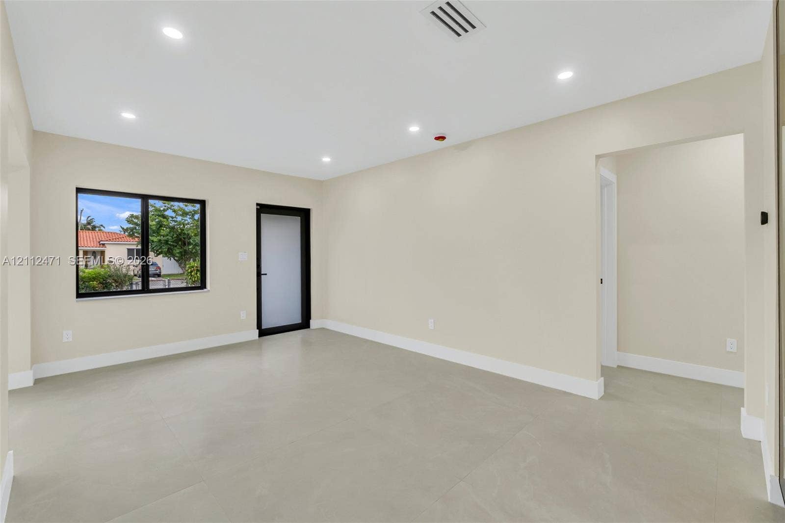 Open-concept room featuring neutral paint, large-format tile flooring, recessed ceiling lighting, and a door with frosted glass paneling