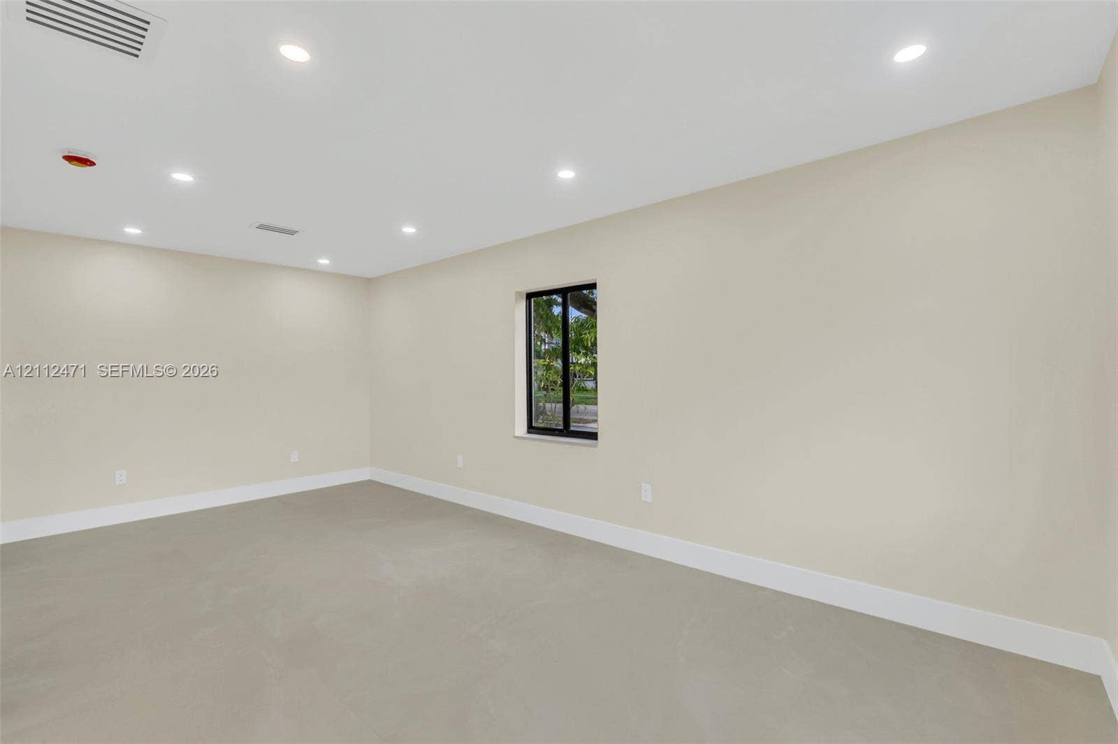 Interior space featuring neutral wall paint, smooth concrete flooring, recessed lighting, and a single window with a black frame