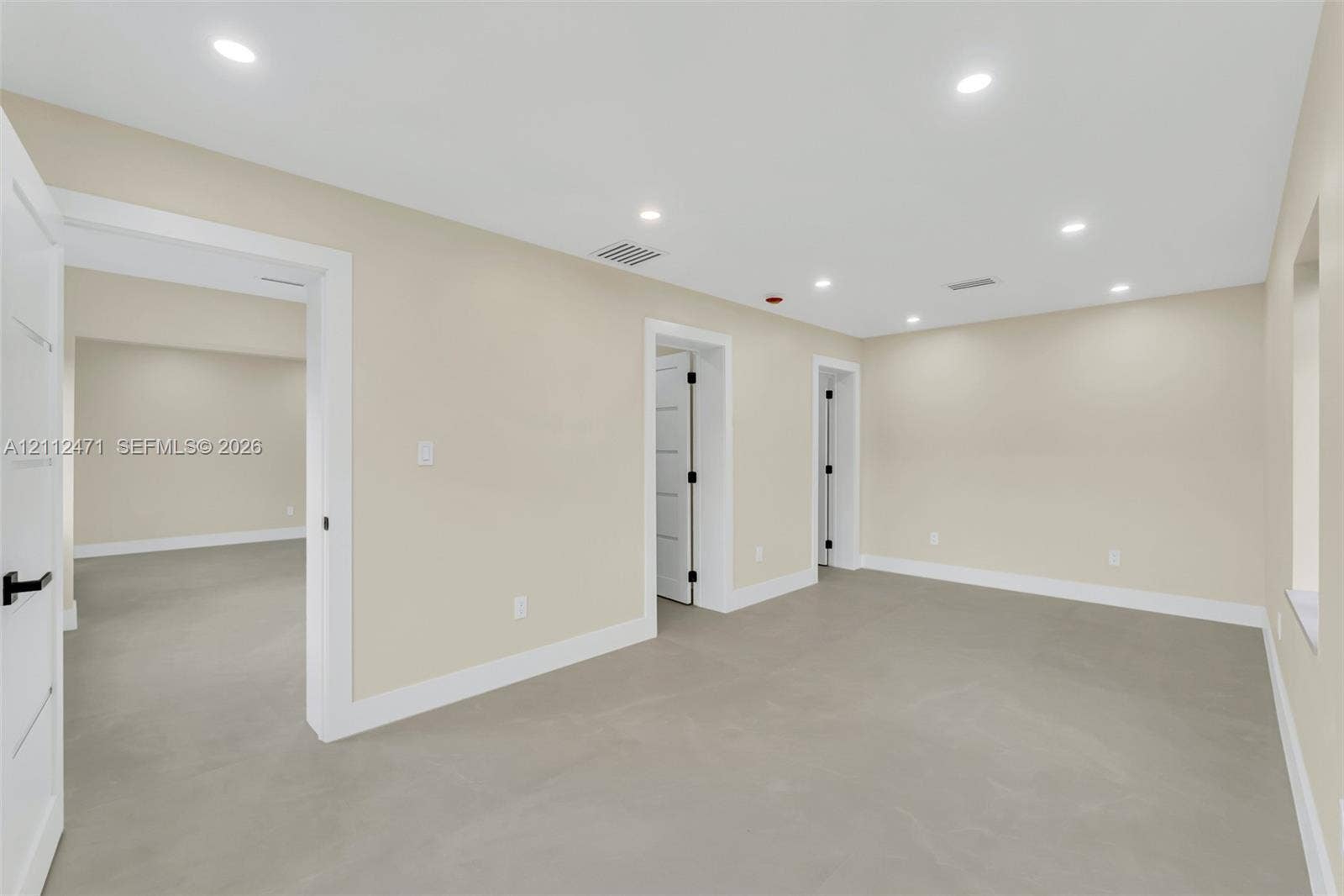 Interior room featuring recessed ceiling lighting, light-toned flooring, and multi-panel interior doors with matte black hardware