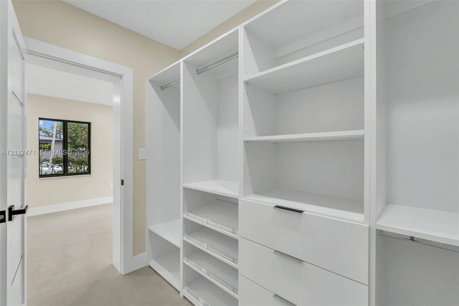 Custom walk-in closet featuring white built-in shelving, integrated garment rods, tiered drawer storage, and matte black hardware