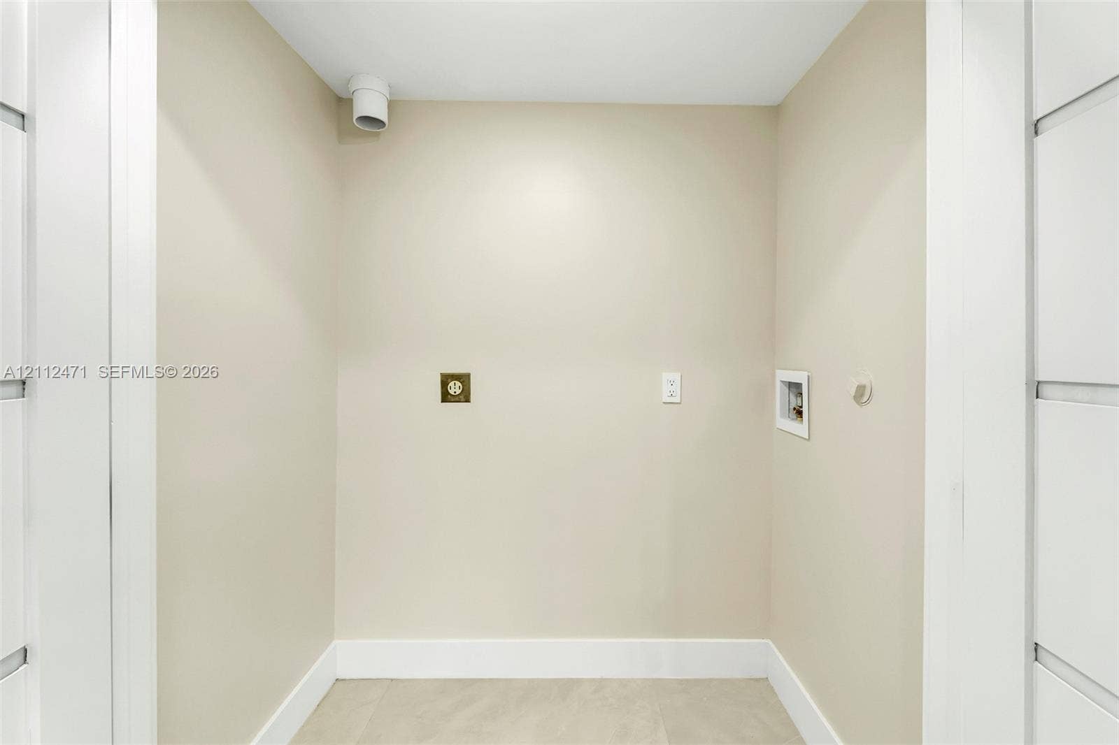Dedicated utility alcove featuring neutral wall finishes, 220-volt electrical outlet, and plumbing hookups