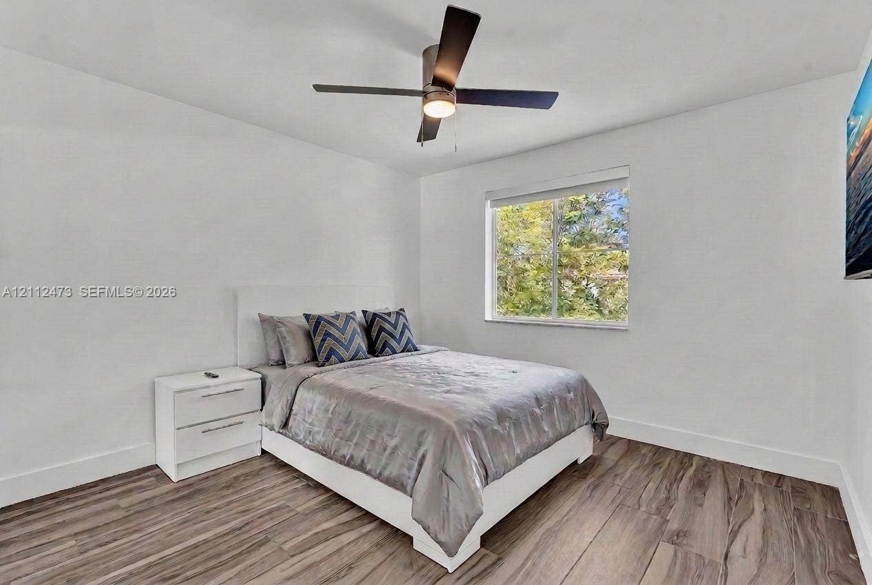 3340 SW 50th Street, Hollywood, Hollywood, FL 33312 Room featuring wood-finish flooring, a neutral color palette, a modern ceiling fan with integrated lighting, and a window with exterior greenery