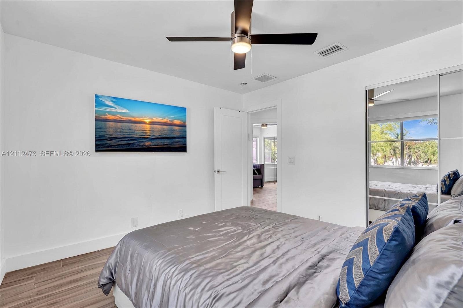 3340 SW 50th Street, Hollywood, Hollywood, FL 33312 Wood-finish flooring, ceiling fan with integrated lighting, and sliding mirror-paneled closet doors