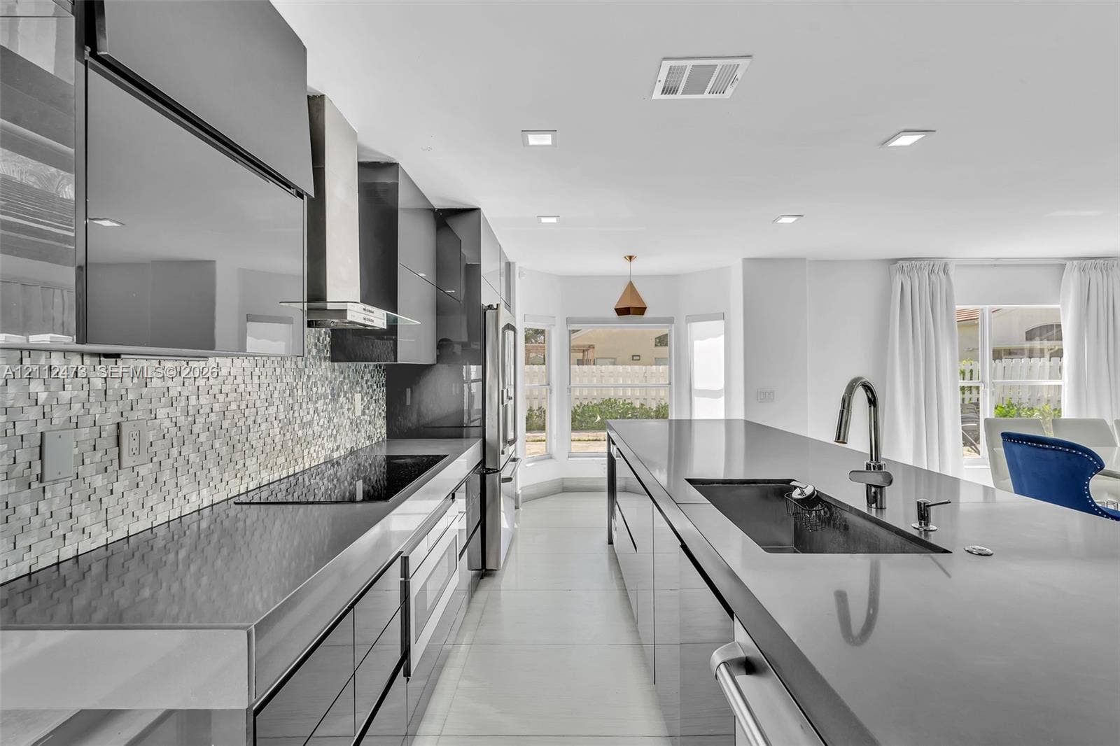 3340 SW 50th Street, Hollywood, Hollywood, FL 33312 Modern kitchen featuring high-gloss cabinetry, stone countertops, a mosaic tile backsplash, a stainless steel range hood, and a large central island with an undermount sink