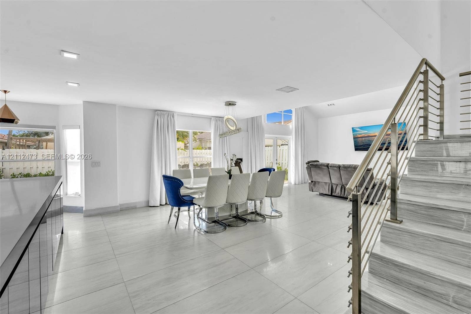3340 SW 50th Street, Hollywood, Hollywood, FL 33312 Open-concept interior featuring large-format tile flooring, vaulted ceilings, recessed lighting, and a staircase with stainless steel cable railing