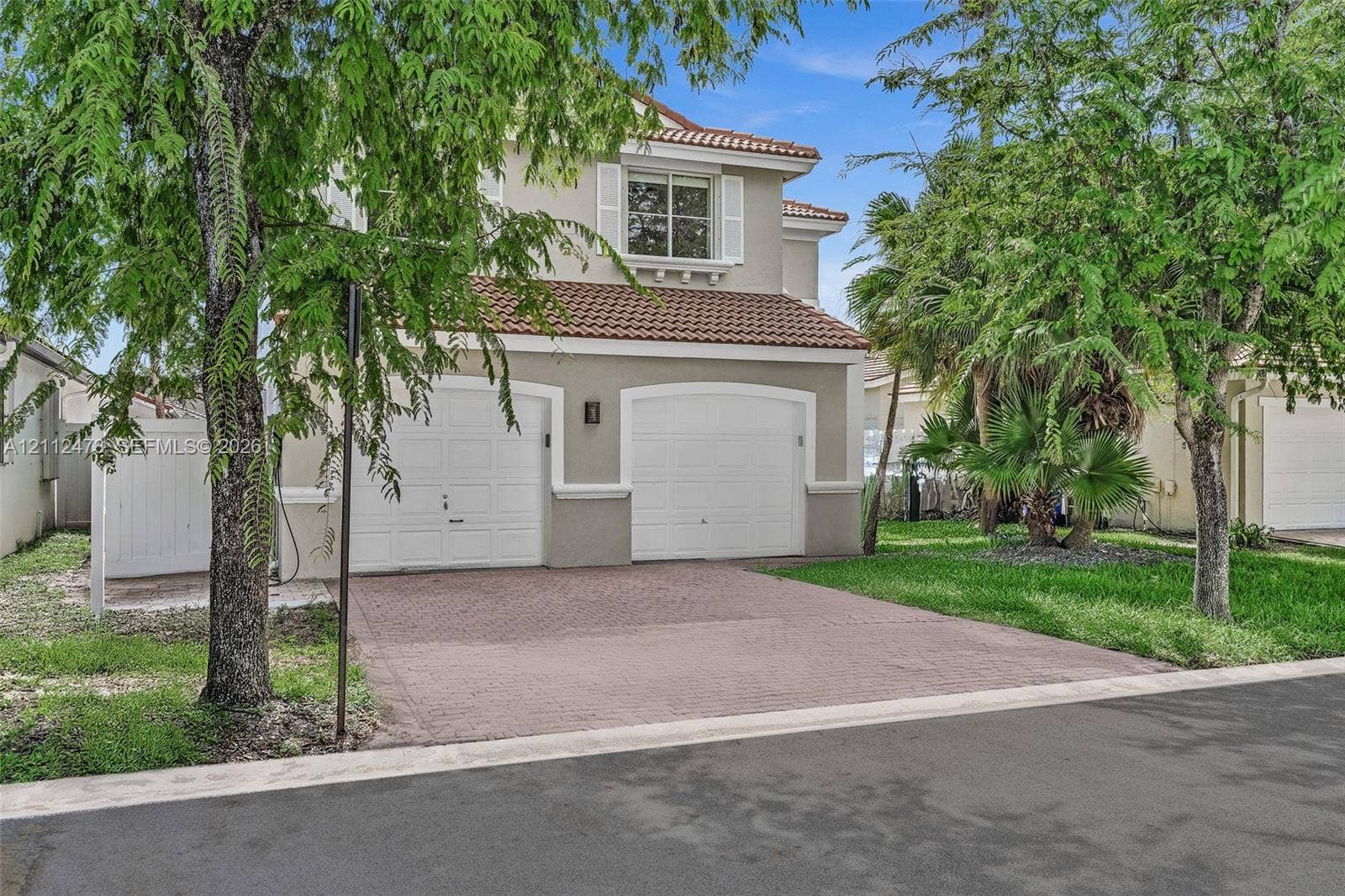 3340 SW 50th Street, Hollywood, Hollywood, FL 33312 Two-story exterior featuring a clay tile roof, stucco siding, arched garage doors, a paved driveway, and decorative window shutters