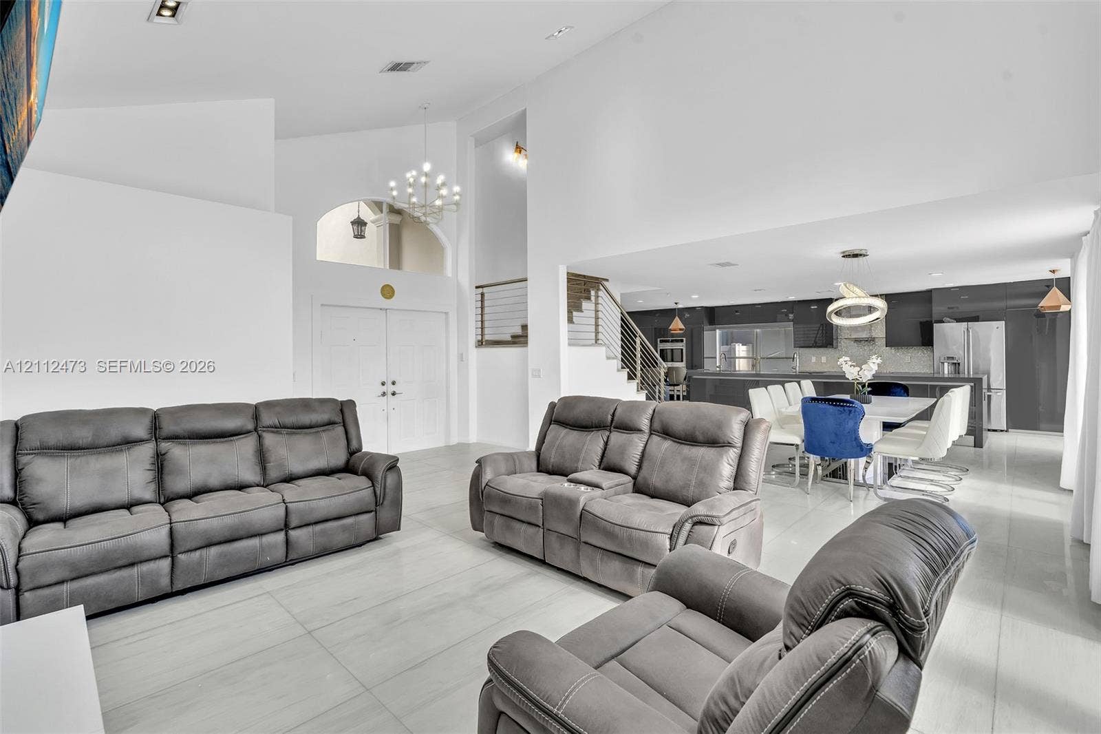 3340 SW 50th Street, Hollywood, Hollywood, FL 33312 Vaulted ceilings, large-format tile flooring, a built-in staircase with a metal railing, recessed lighting, and a modern kitchen featuring a central island