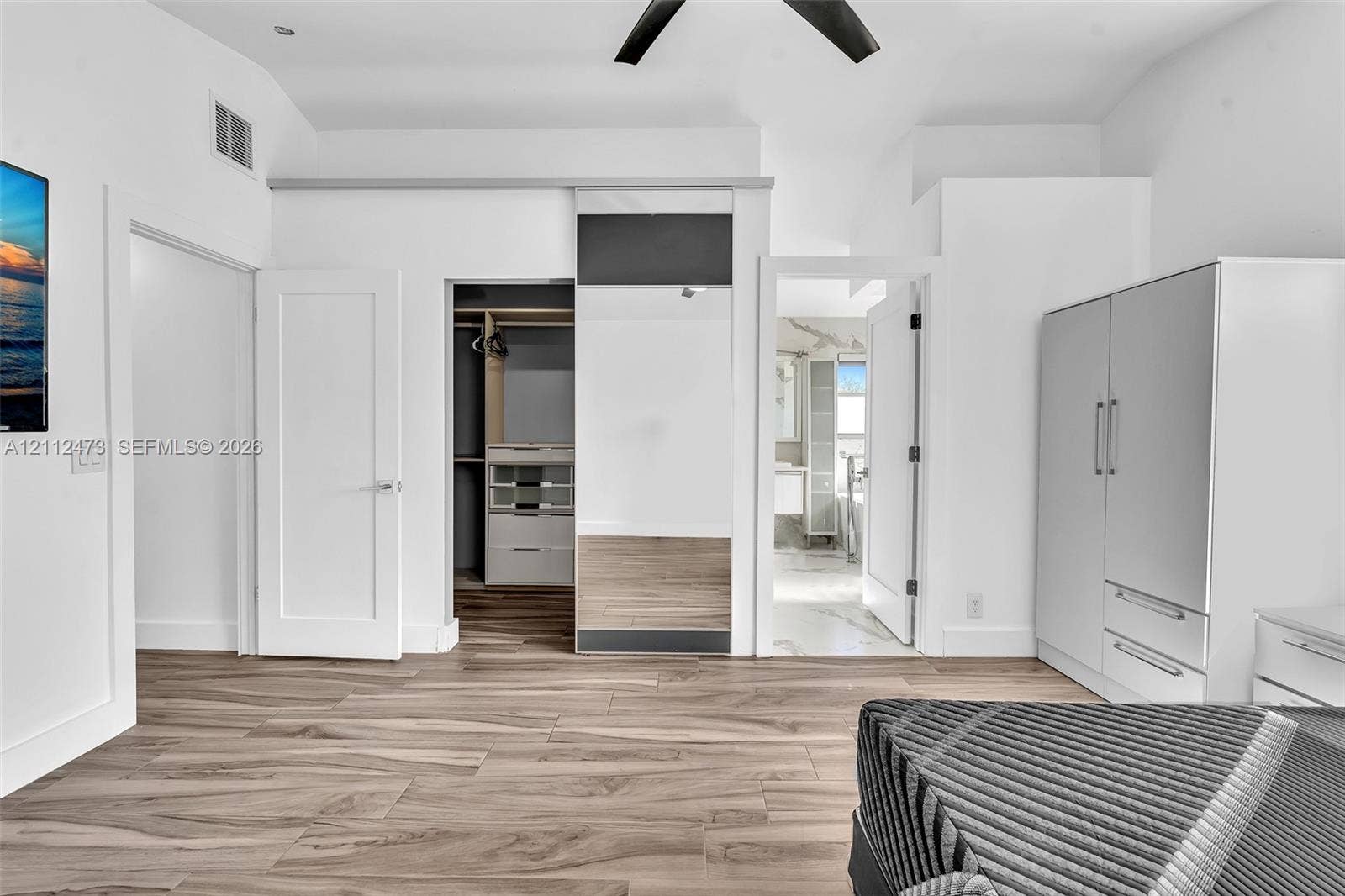 3340 SW 50th Street, Hollywood, Hollywood, FL 33312 Wood-finish flooring, vaulted ceiling with a matte black fan, sliding mirrored closet door, and built-in closet organization system