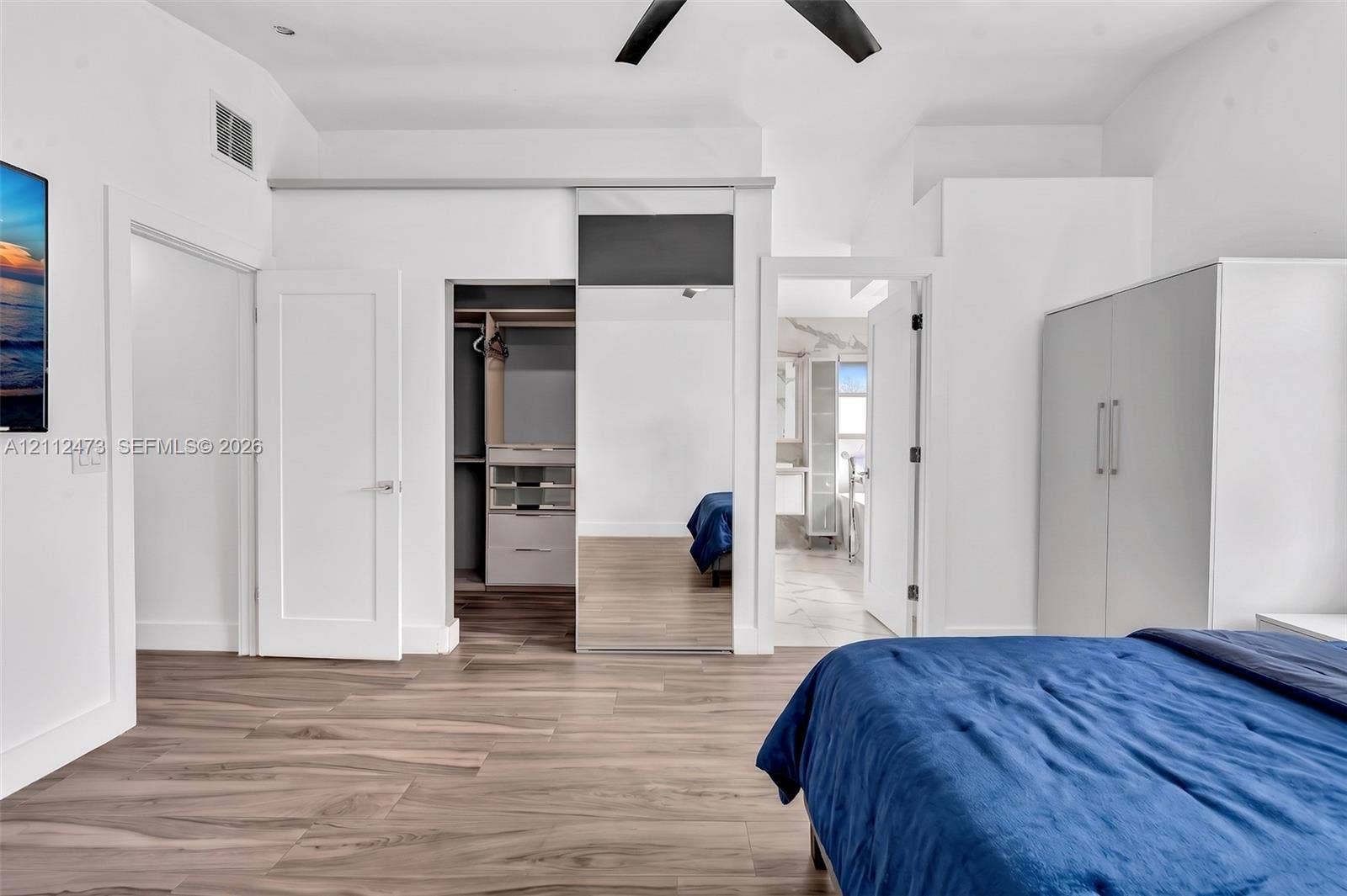3340 SW 50th Street, Hollywood, Hollywood, FL 33312 Wood-finish flooring, vaulted ceilings with a matte black ceiling fan, and built-in closet system with mirrored sliding doors