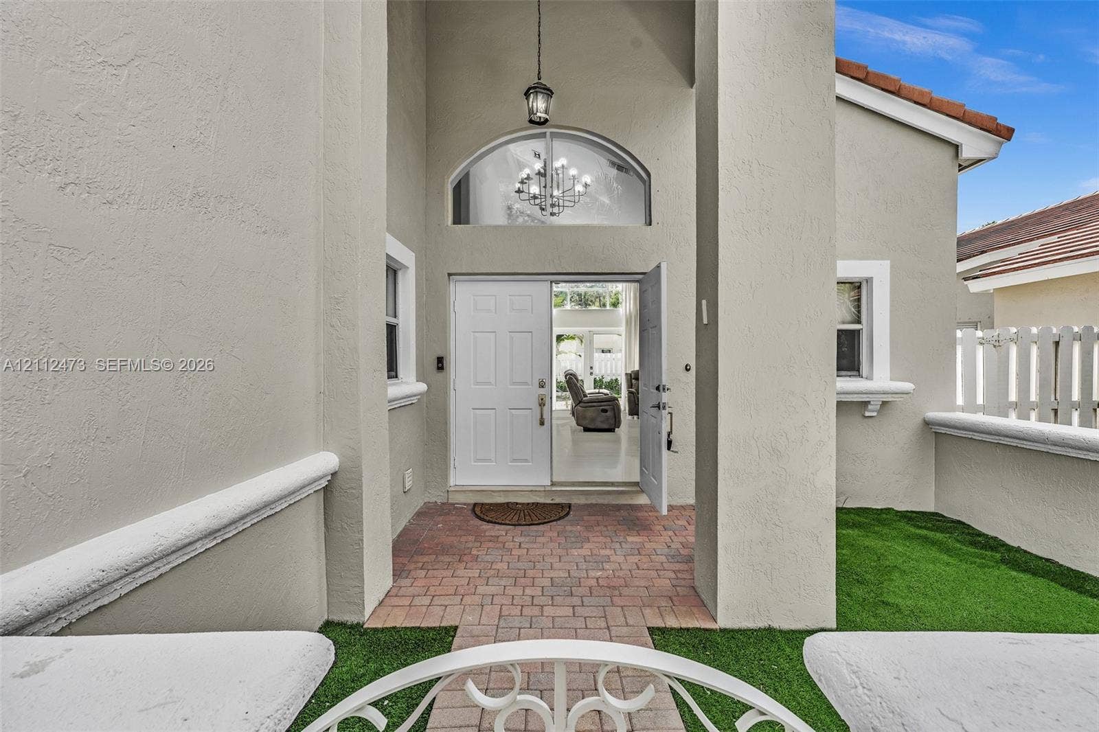3340 SW 50th Street, Hollywood, Hollywood, FL 33312 Stucco entryway featuring a covered porch, brick paver flooring, arched transom window, and an attached lantern-style pendant light