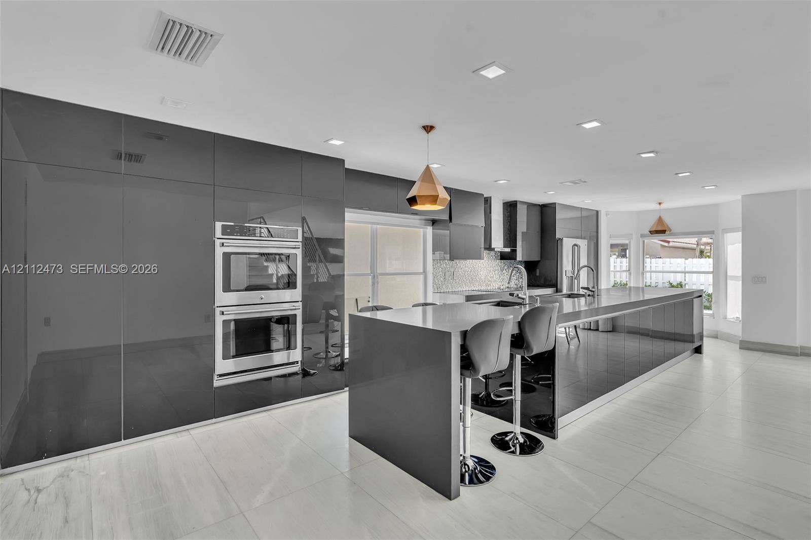 3340 SW 50th Street, Hollywood, Hollywood, FL 33312 Contemporary kitchen featuring high-gloss cabinetry, stainless steel double wall ovens, a large kitchen island with quartz countertops, recessed lighting, and large-format tile flooring