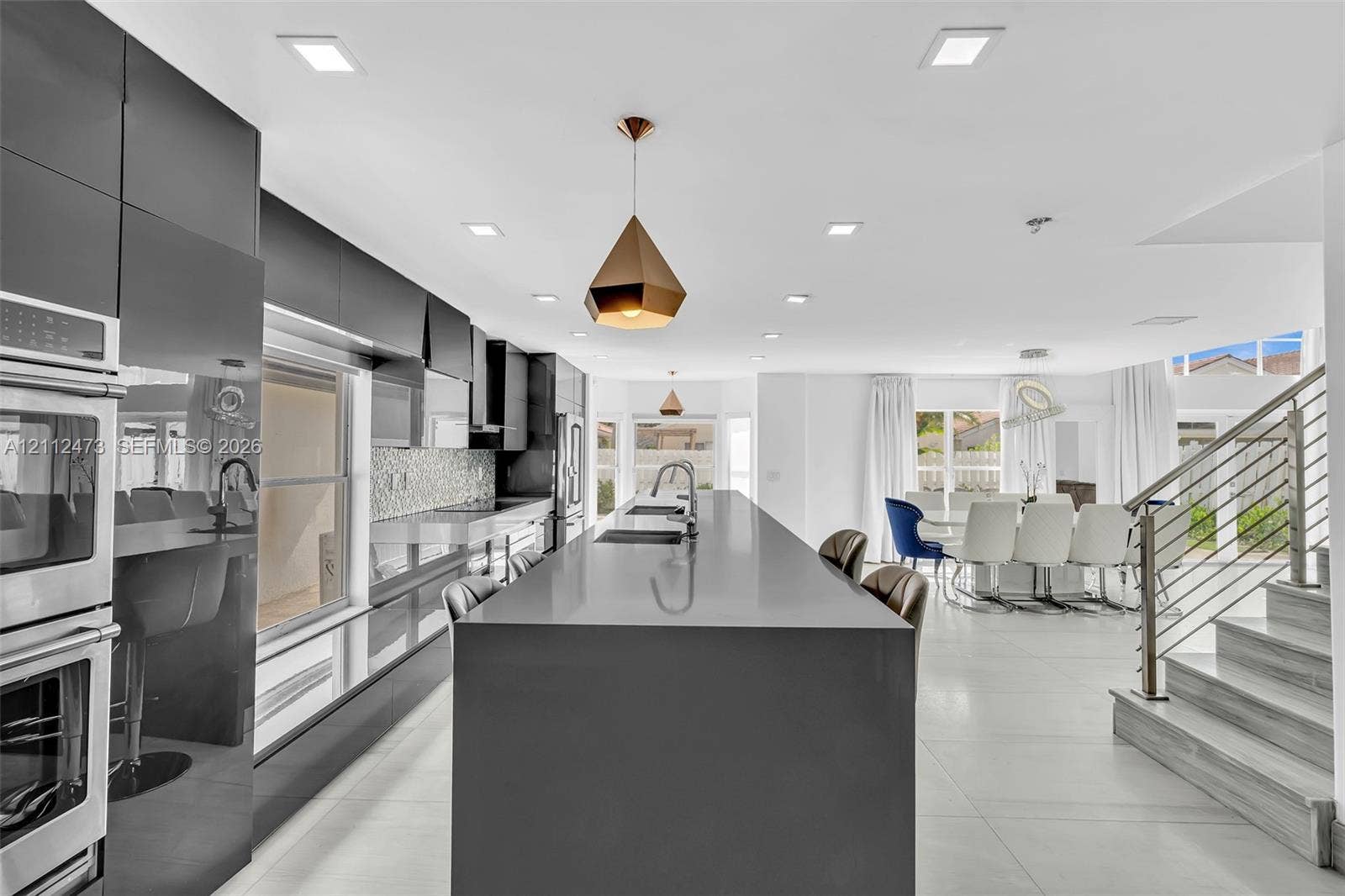 3340 SW 50th Street, Hollywood, Hollywood, FL 33312 Kitchen featuring high-gloss cabinetry, expansive waterfall-edge island, built-in double ovens, recessed lighting, and large-format tile flooring
