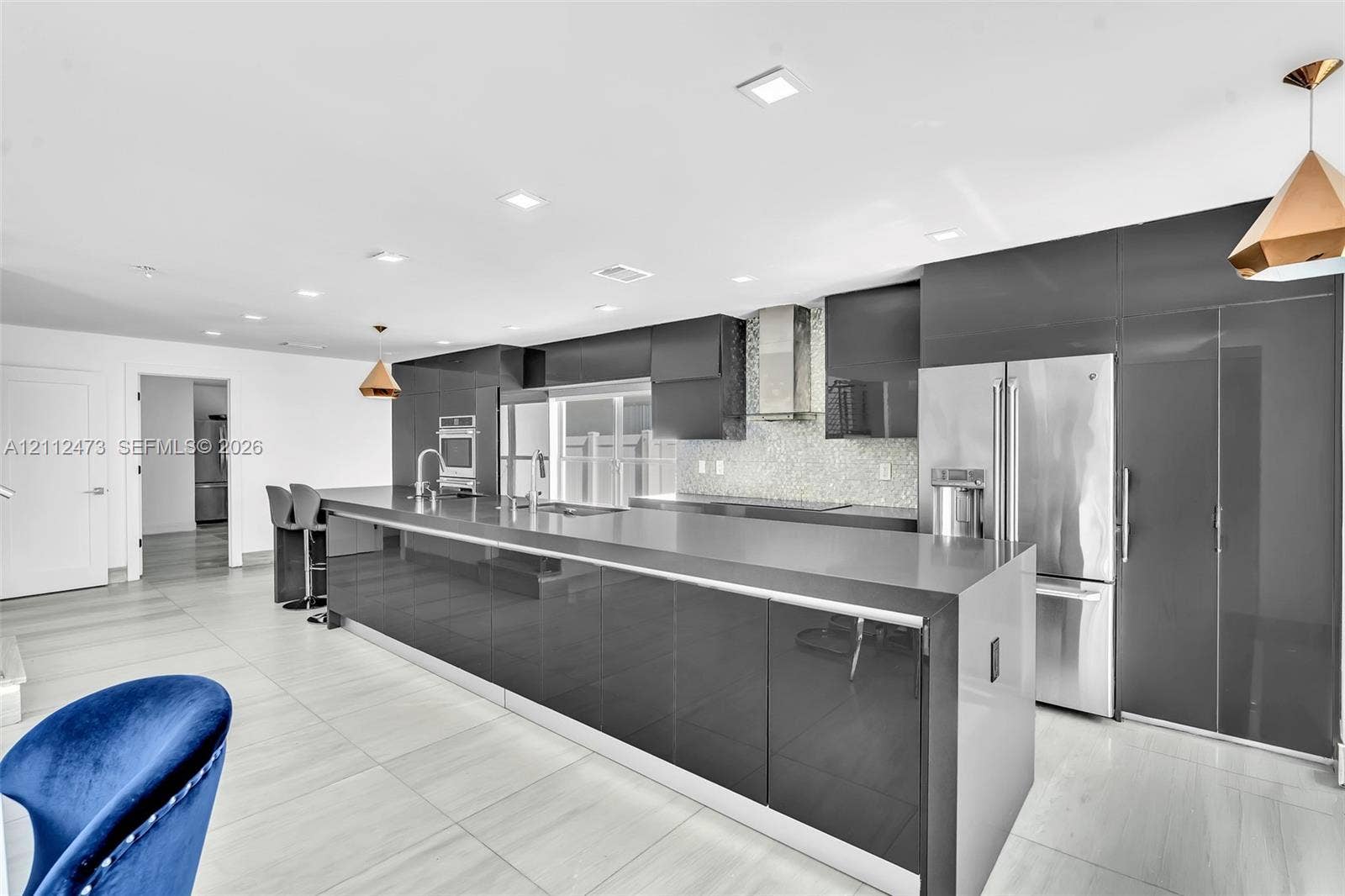 3340 SW 50th Street, Hollywood, Hollywood, FL 33312 Contemporary kitchen featuring high-gloss cabinetry, stainless steel appliances, a stone countertop island, recessed lighting, and large-format tile flooring