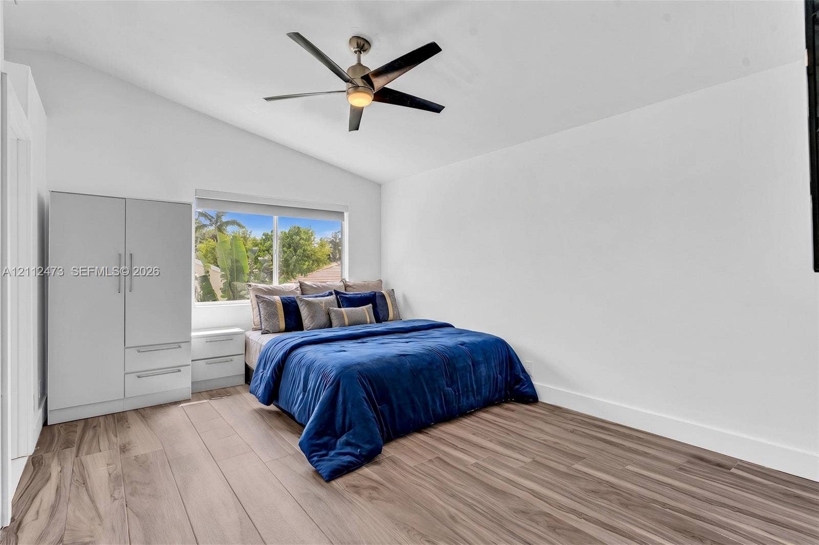 3340 SW 50th Street, Hollywood, Hollywood, FL 33312 Vaulted ceiling featuring a central five-blade ceiling fan, wood-finish flooring, and a large picture window
