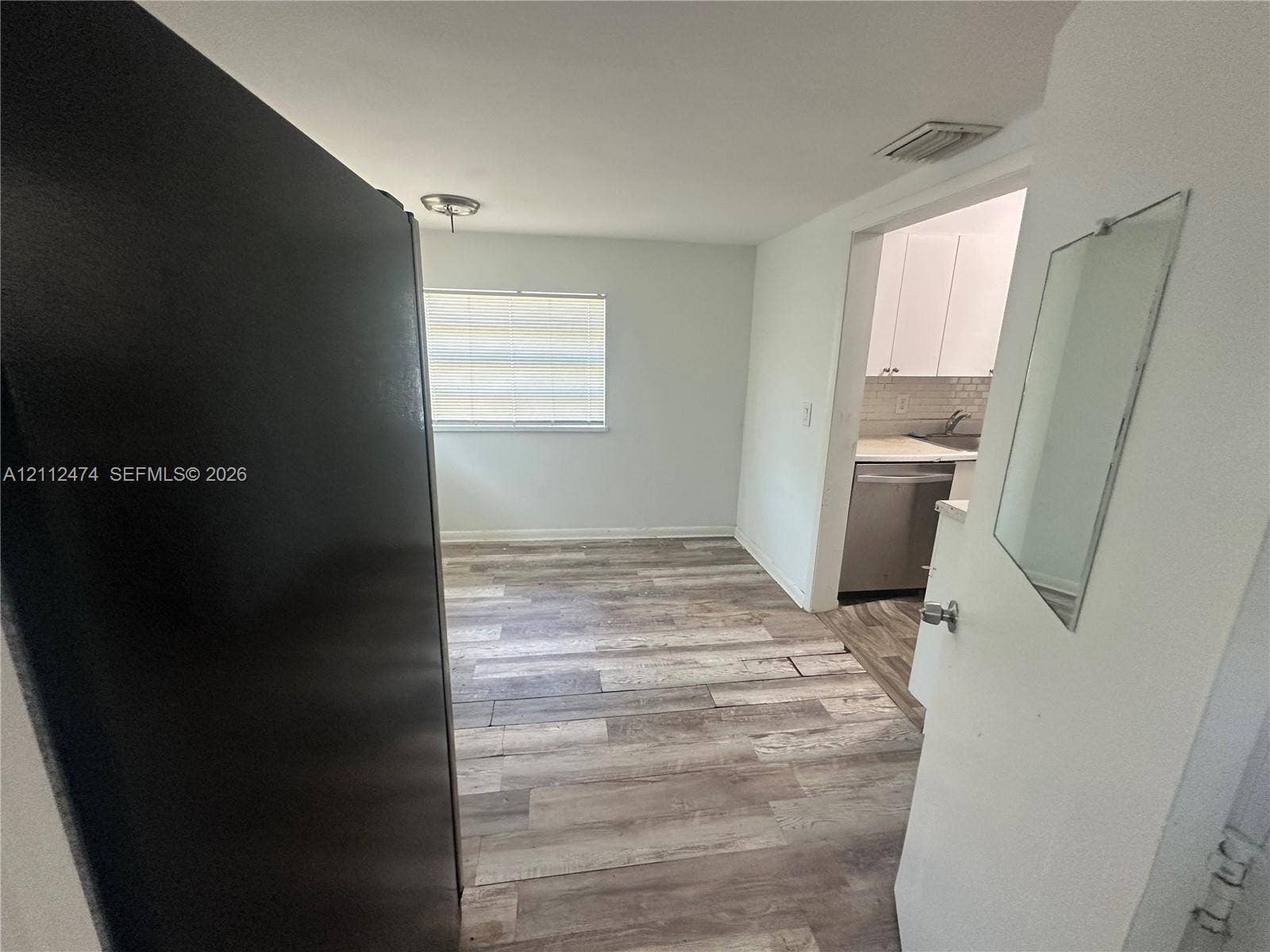 Wood-finish flooring, horizontal window blinds, and stainless steel kitchen appliances